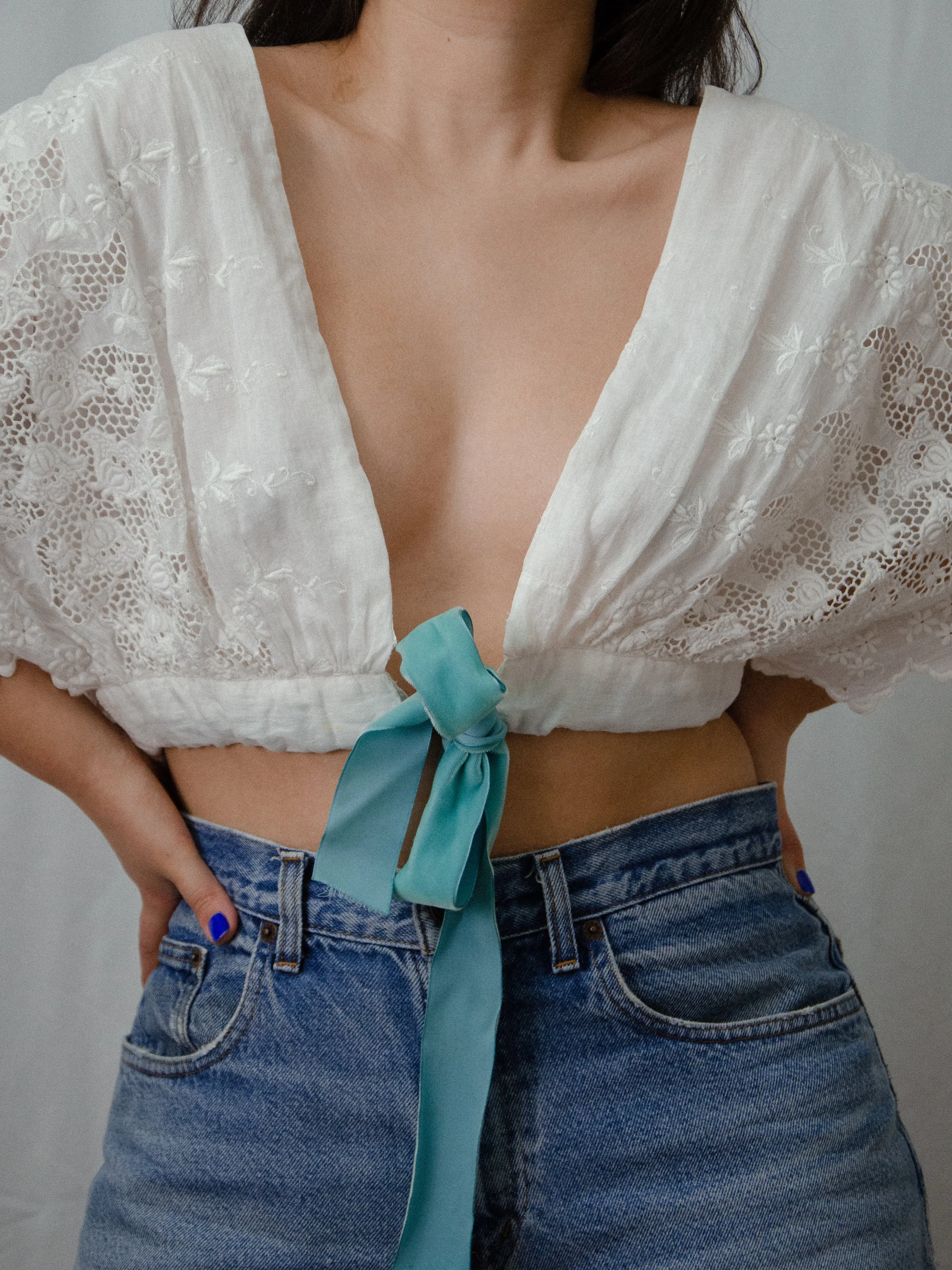 Close-up of the antique white wrap blouse's deep V front tied with an aqua silk velvet ribbon.