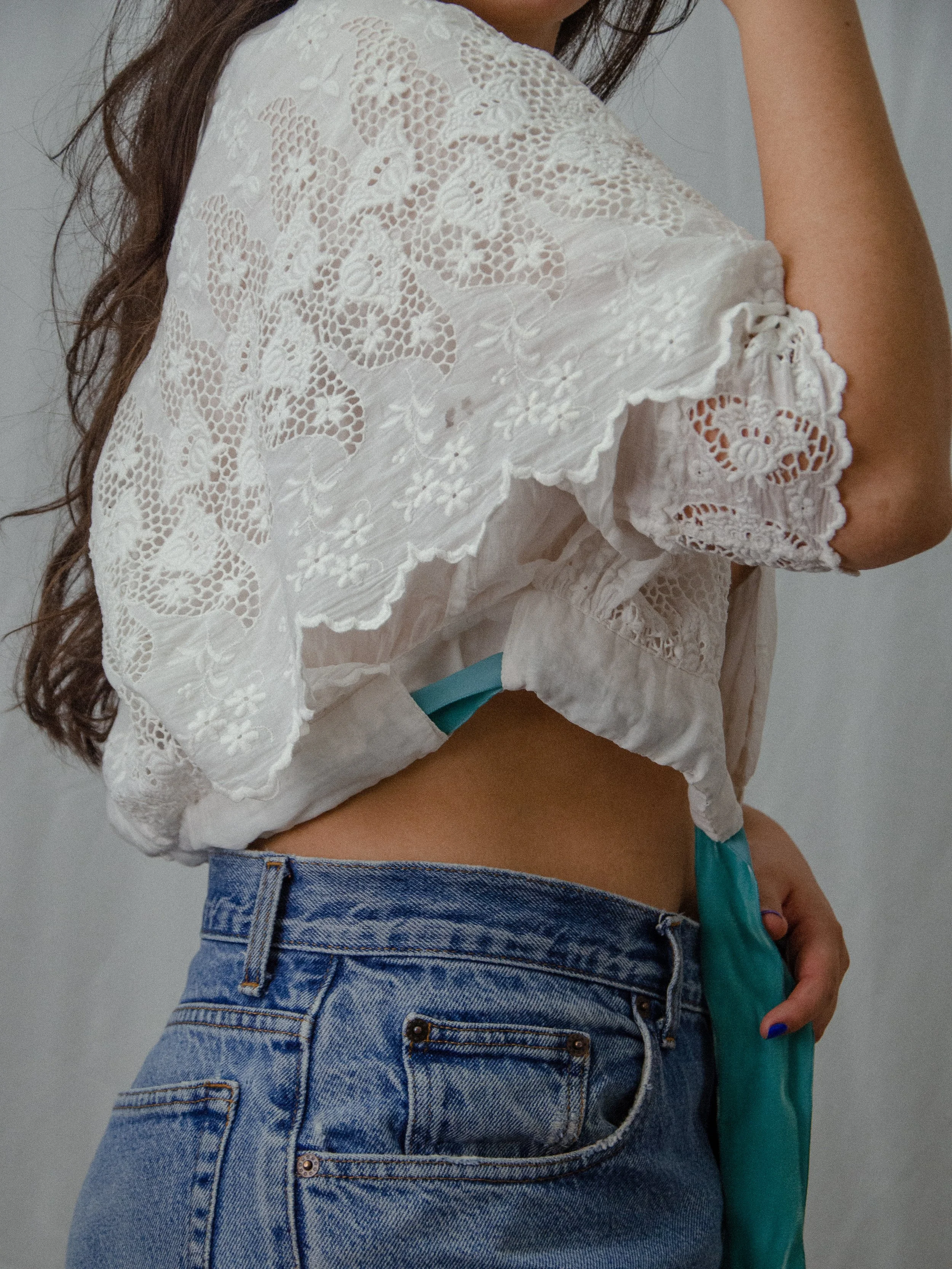 Back view of the antique cotton wrap blouse on a model with arm raised, showing the floral lace sleeve.
