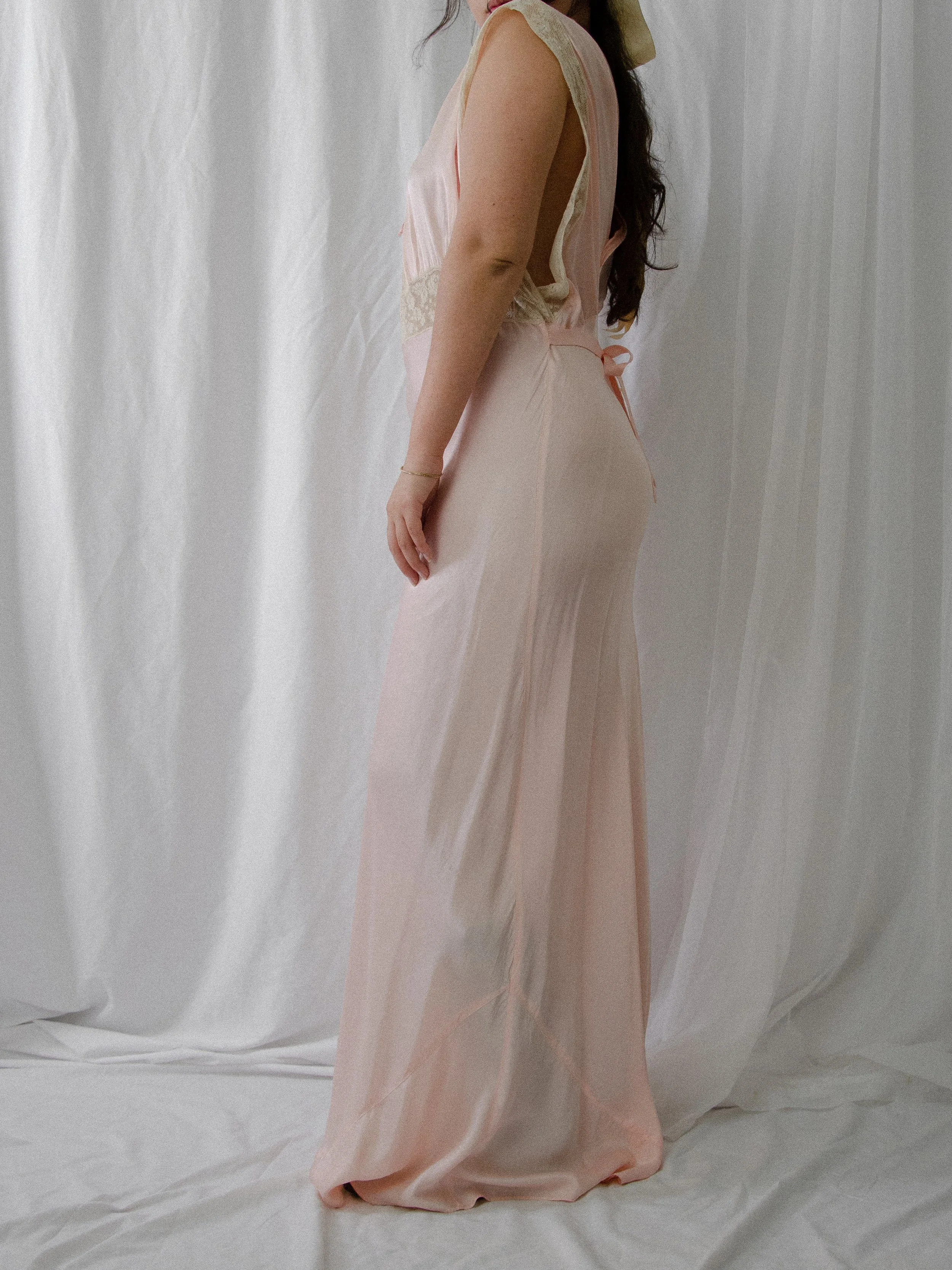 Side view of the 1940s pink satin slip dress on a model, showing the long fluid skirt.