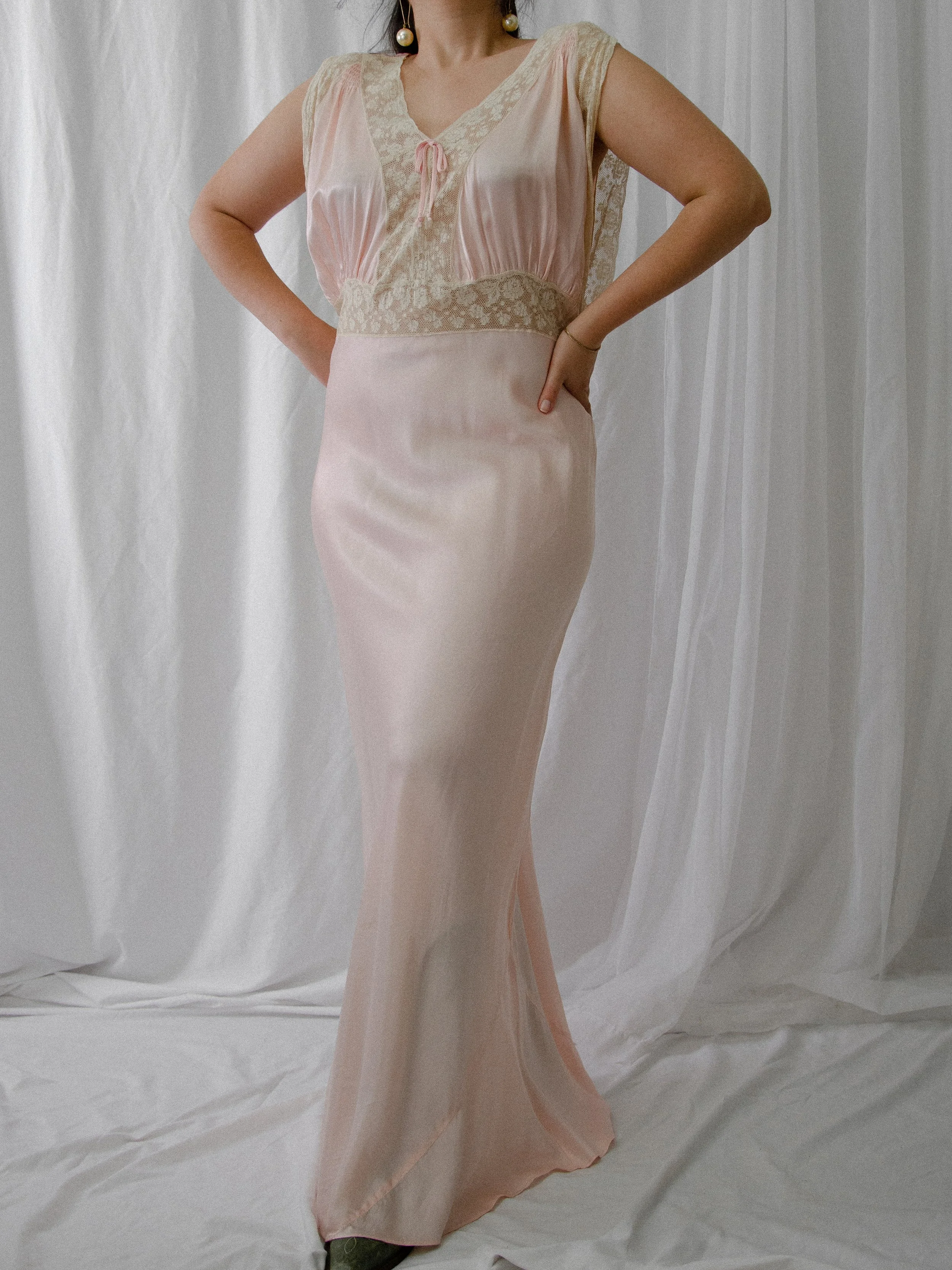 Front view of the 1940s pink satin bias-cut slip dress on a model with hands on hips.