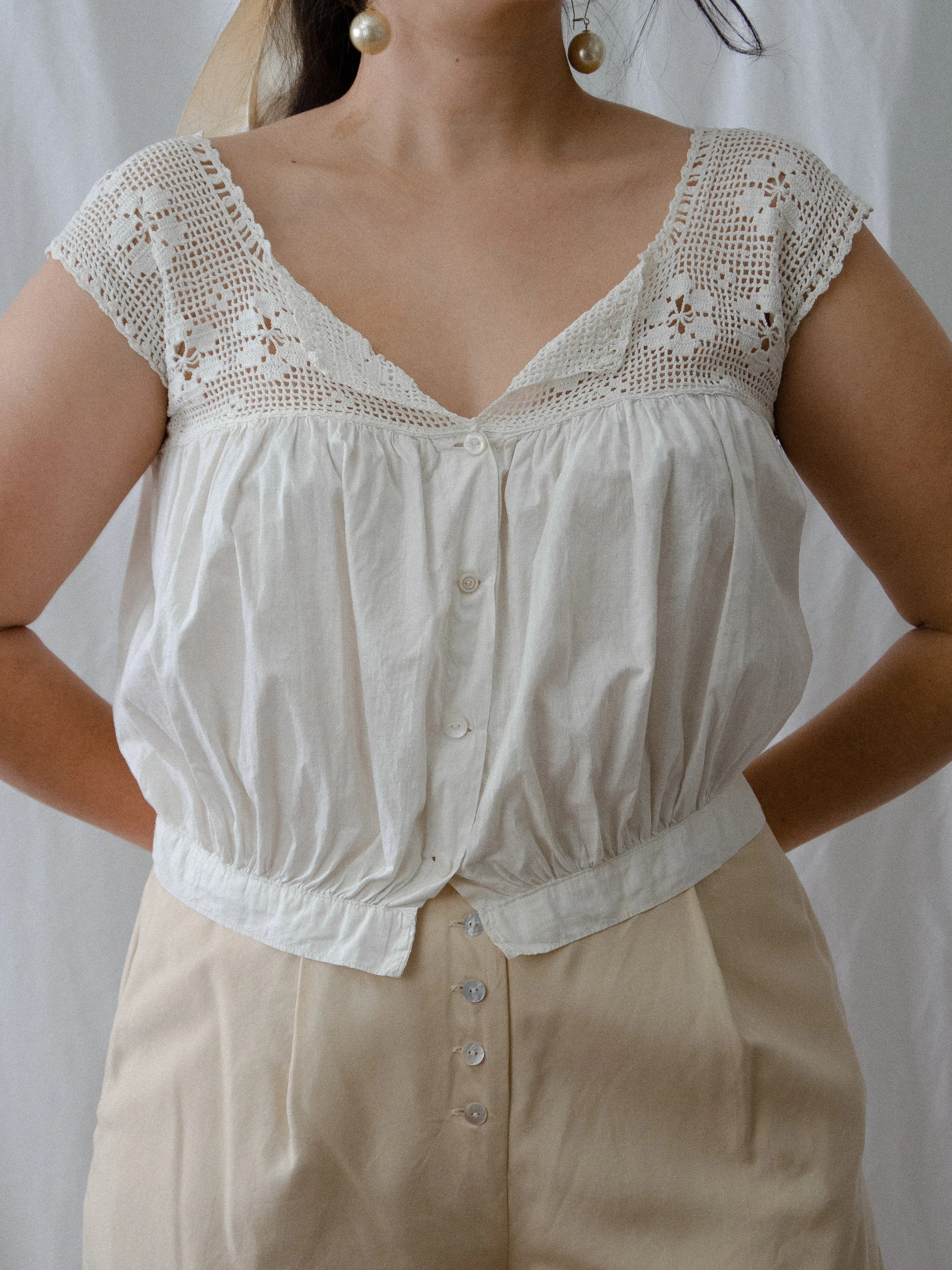 Front view of the Edwardian white cotton tank with crochet yoke on a model with hands on hips.