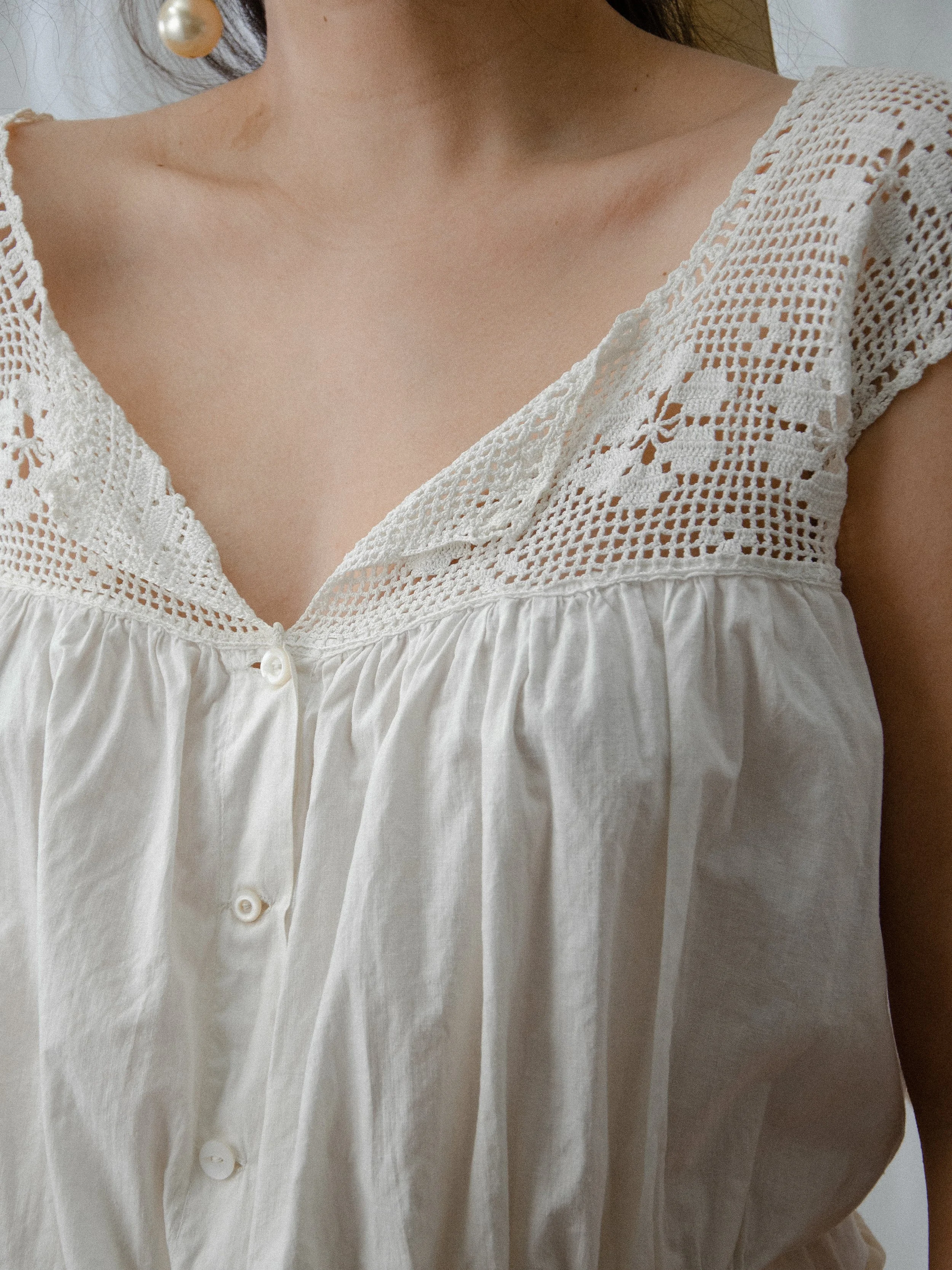 Close-up of the Edwardian crochet tank's V-neck filet crochet yoke with floral motifs and small buttons.