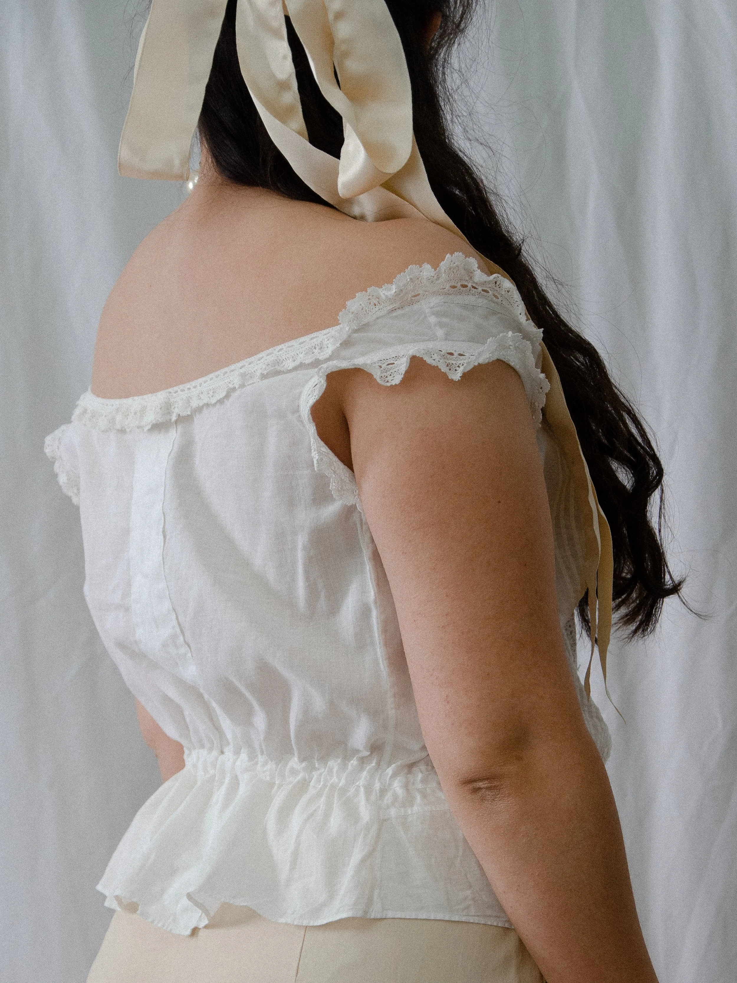 Back view of the antique white cotton corset cover on a model, showing the lace-trimmed neckline.