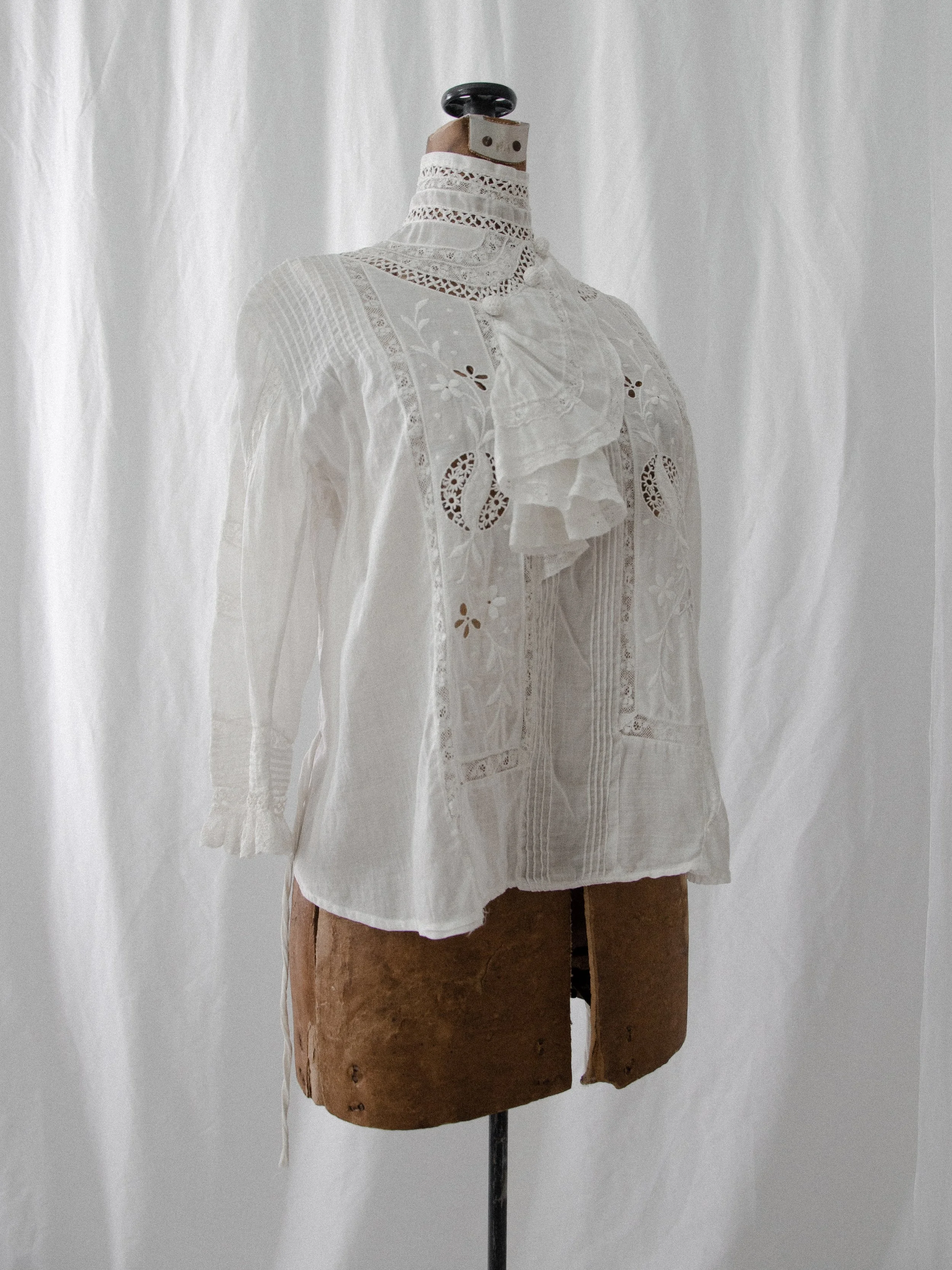 Three-quarter front view of the 1910s Edwardian ascot blouse on a dress form, showing the mock neck.