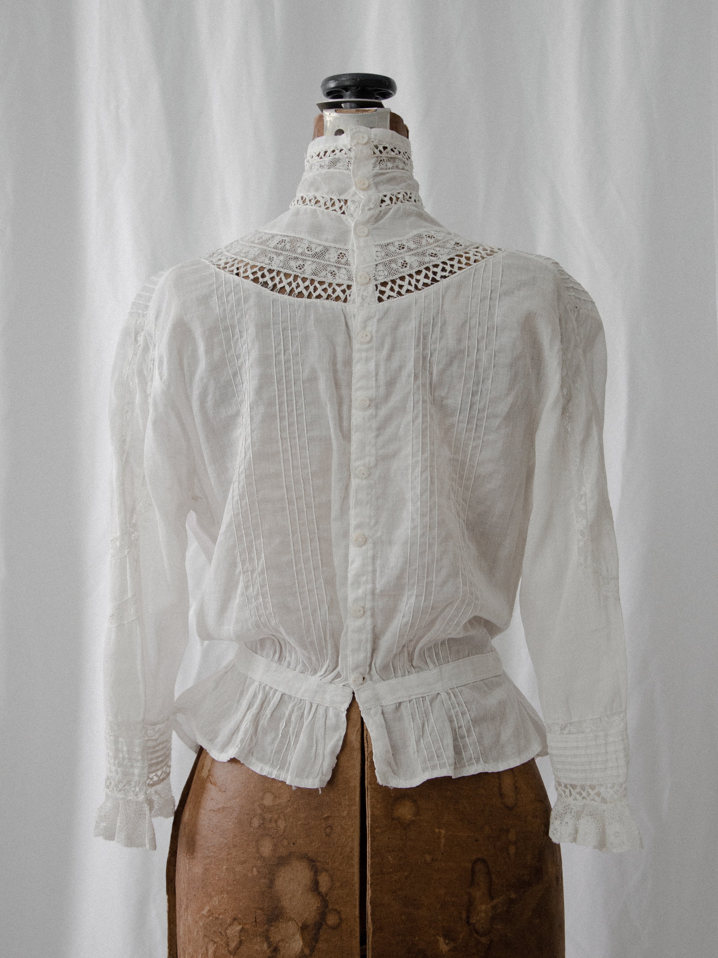 Back view of the Edwardian ascot blouse on a dress form, showing the high lace collar and peplum.