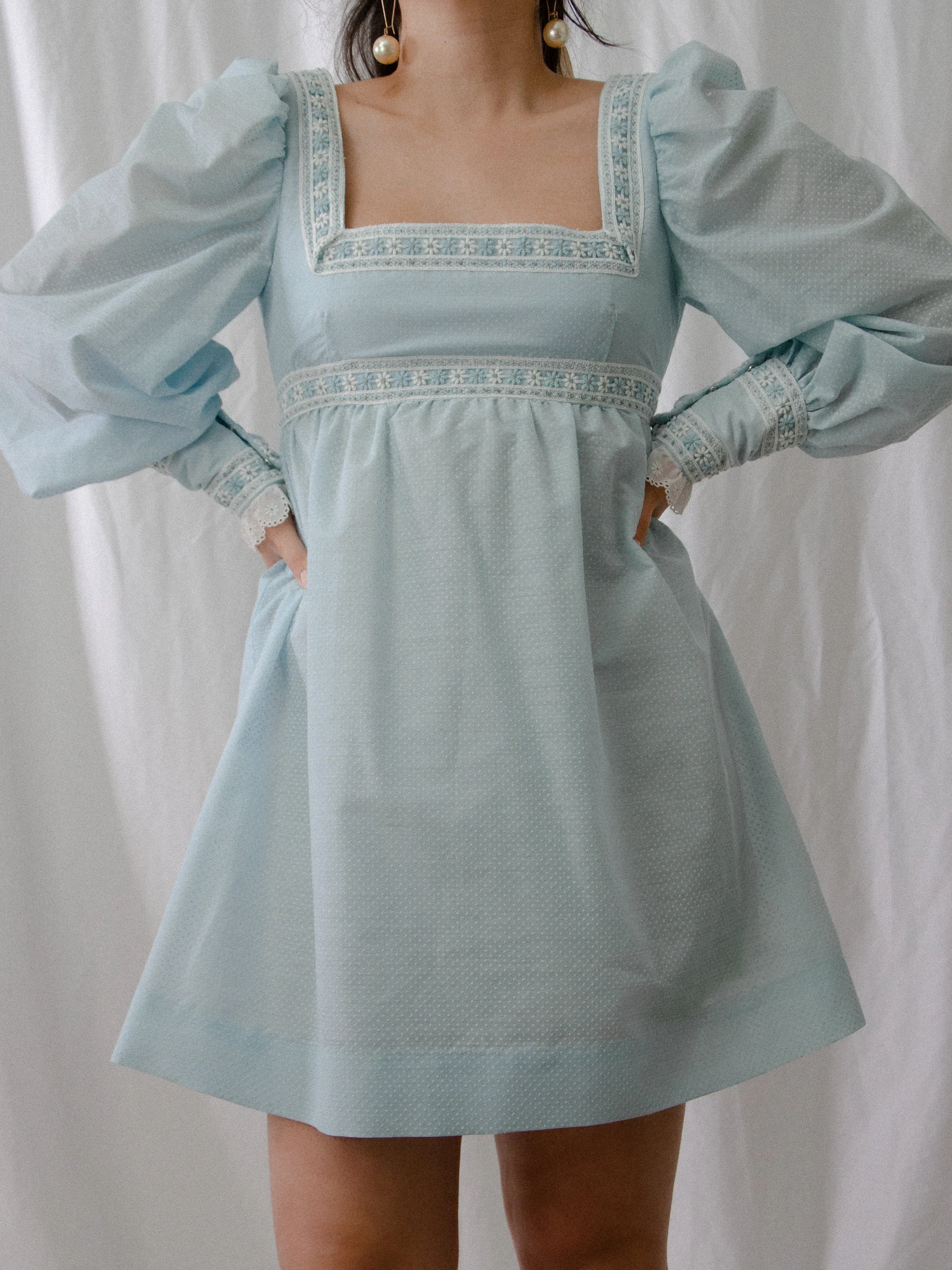 Front view of the 1970s Bluebonnet mini dress on a model with hands on hips, showing the full skirt.