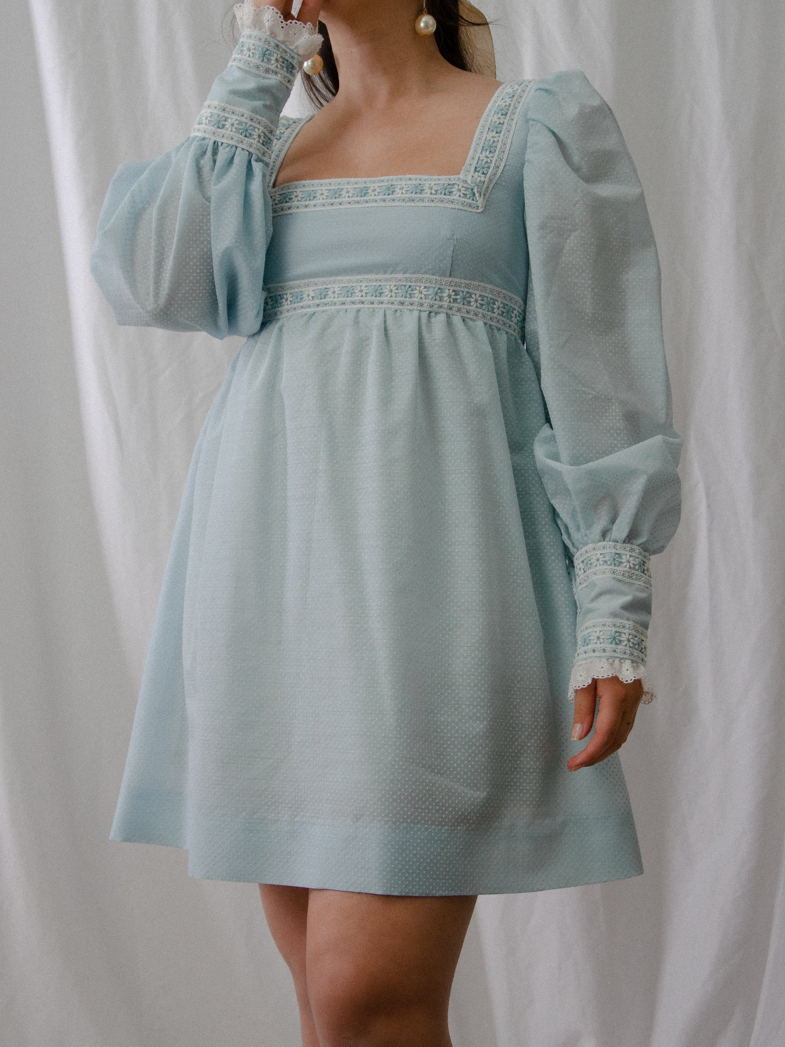 1970s sky blue mini dress on a model with one arm raised, showing the long puffed sleeves.