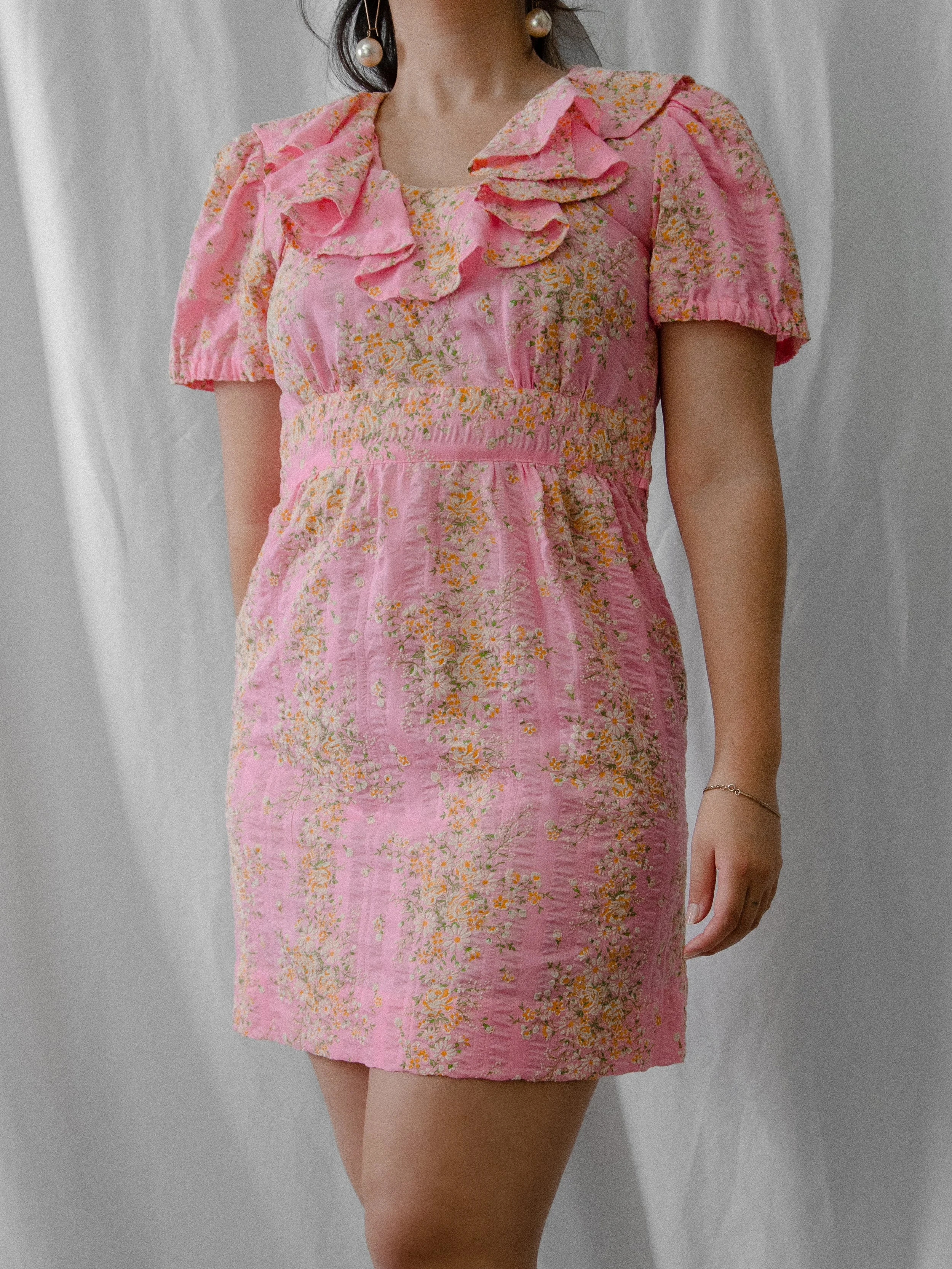 1970s pink floral ruffle neckline mini dress on a model, three-quarter front view.