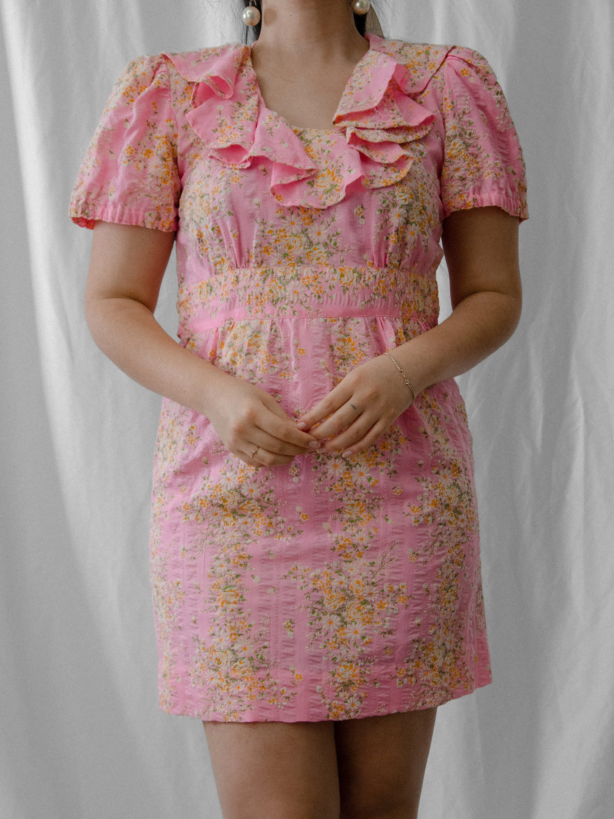 Front view of the 1970s bubblegum pink ruffle mini dress on a model, showing the empire waist.