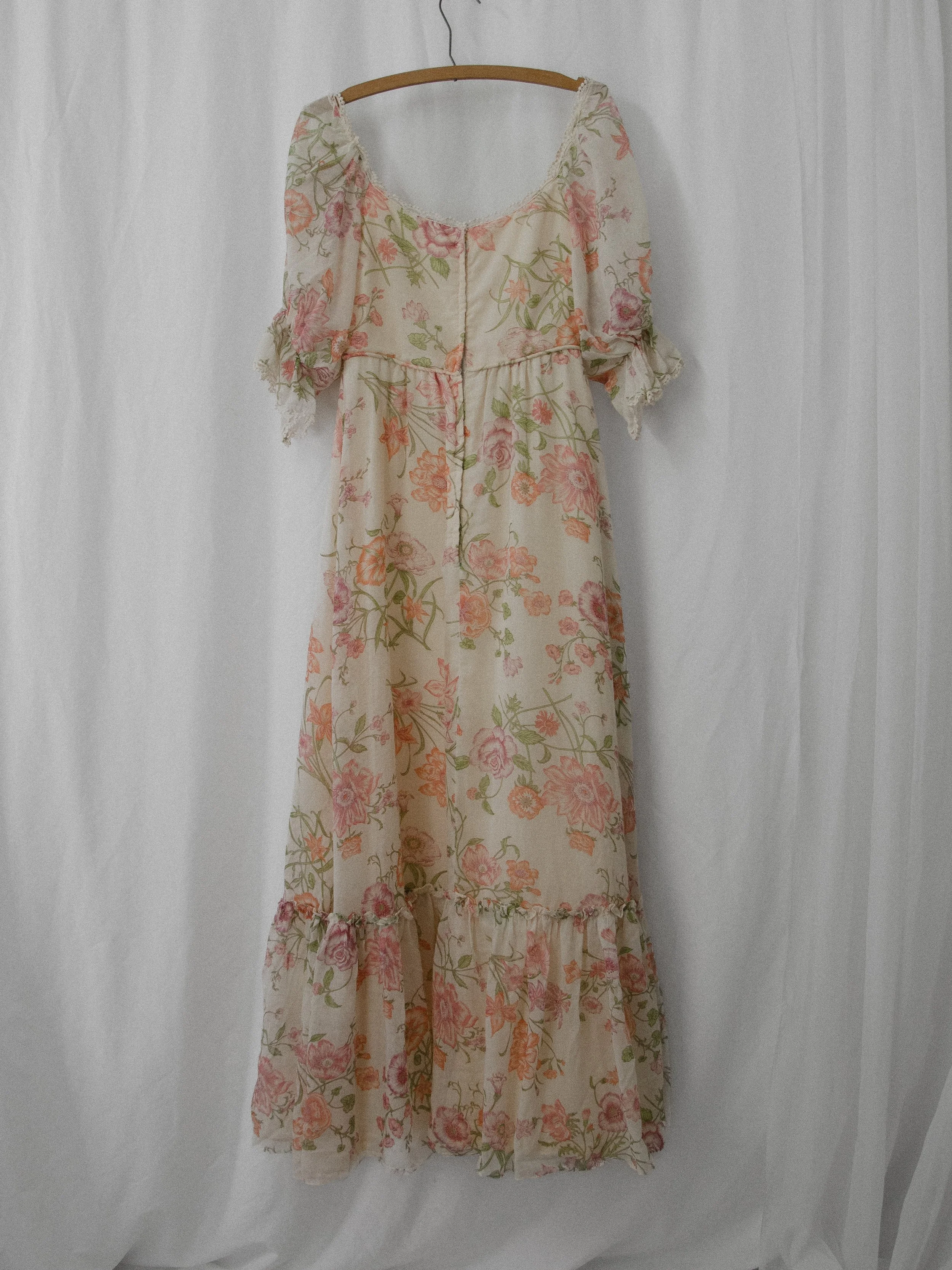 Back view of the 1970s floral puff sleeve dress on a hanger, showing the center back seam and ruffle hem.