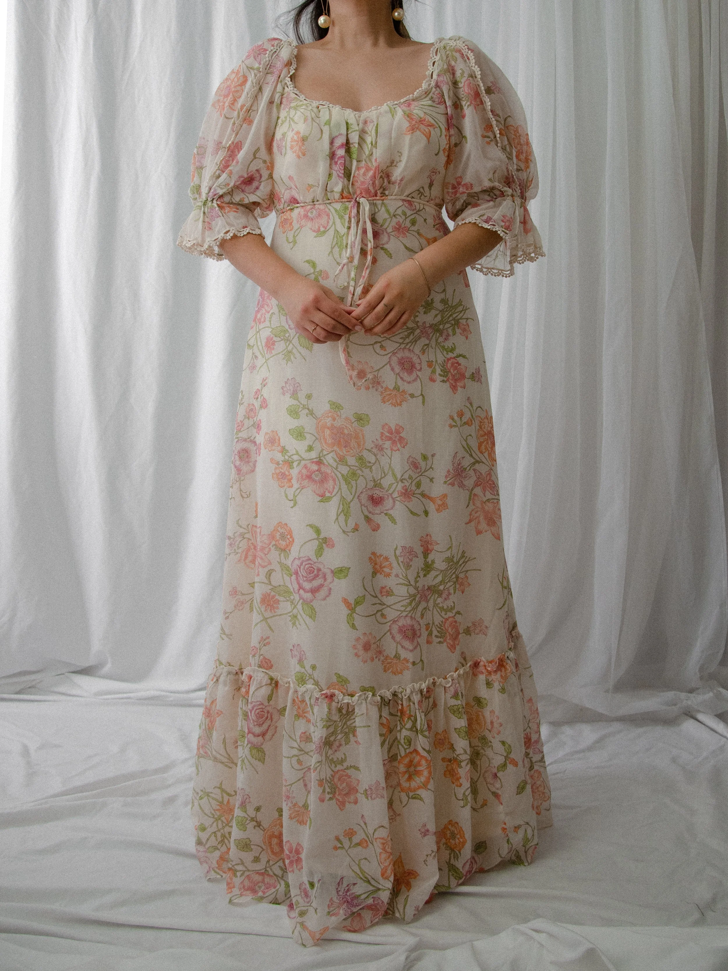 Front view of the 1970s cream garden-floral maxi dress on a model, showing the tiered ruffle hem.