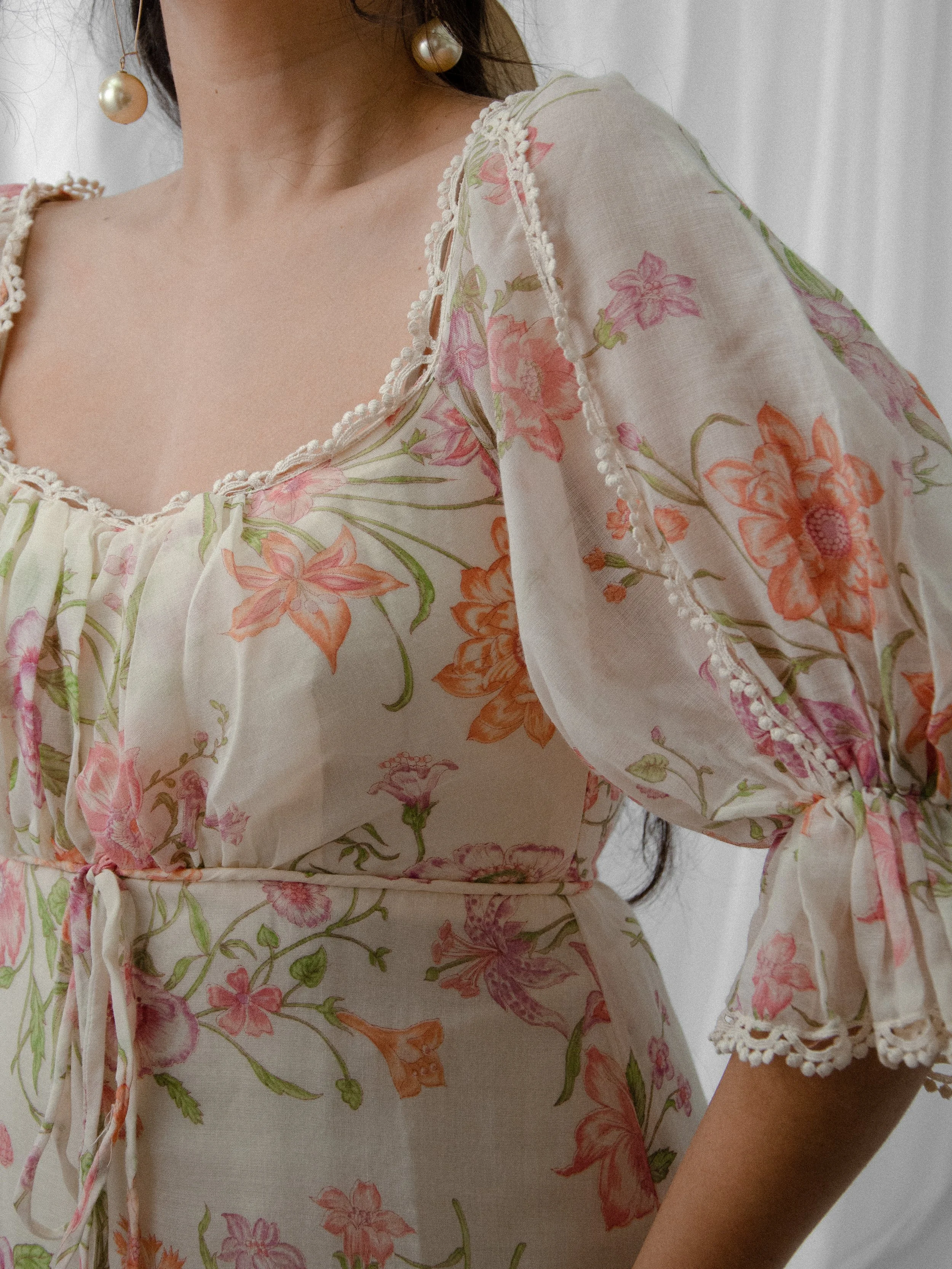 Close-up of the 1970s floral voile dress showing the scoop neckline, lace-trimmed puff sleeve and bust tie.