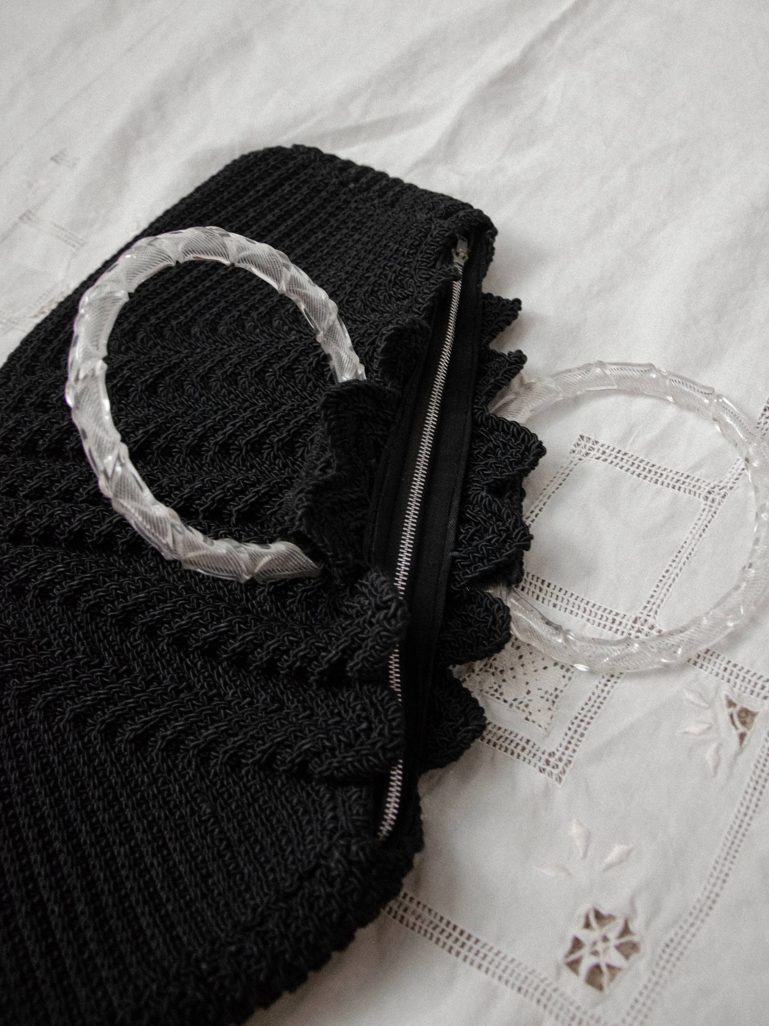Detail of the 1940s black crochet bag laid flat, showing the metal top zipper and lucite handles.