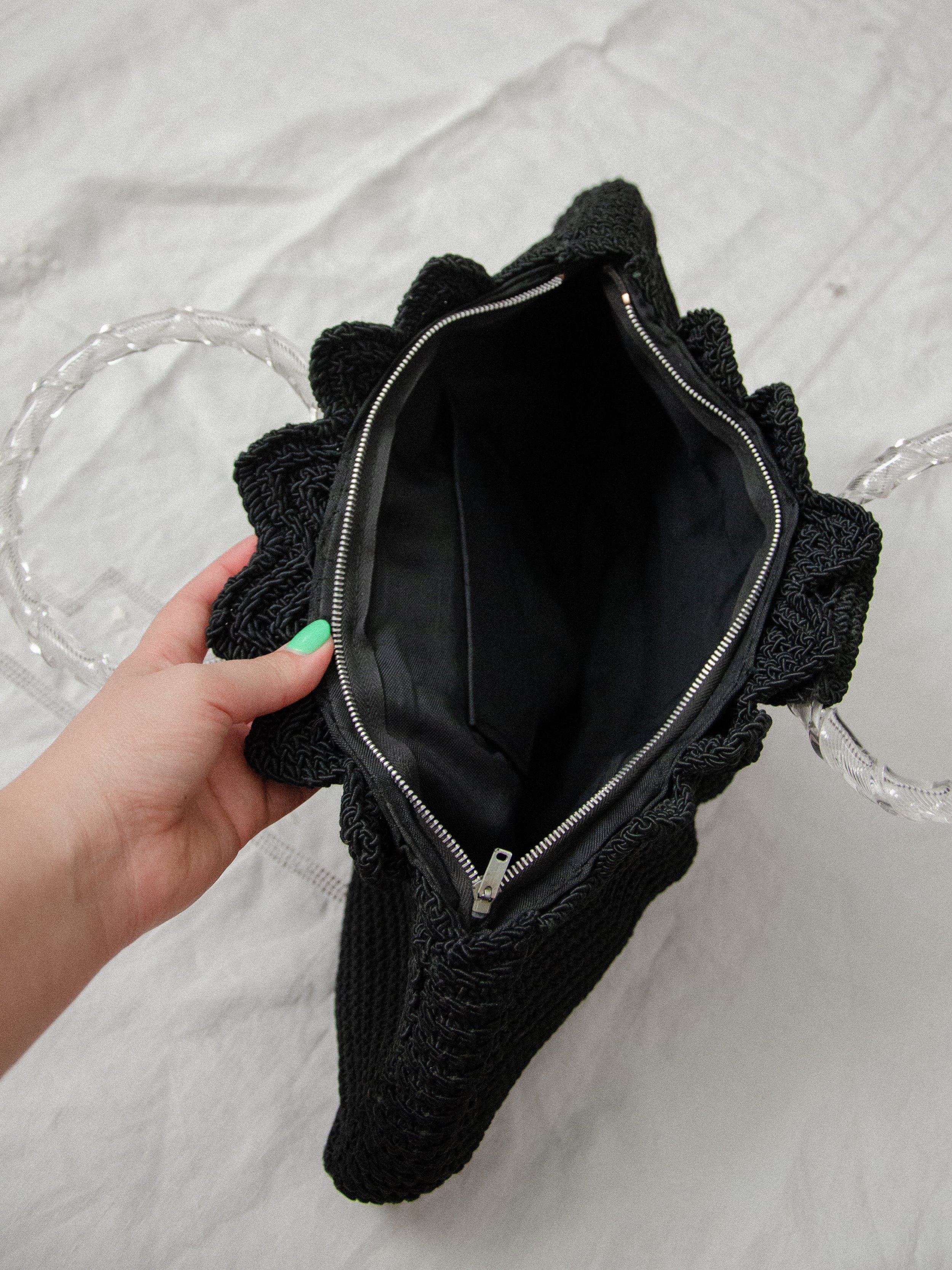 1940s black crochet clamshell bag unzipped and held open, showing the black fabric lining.