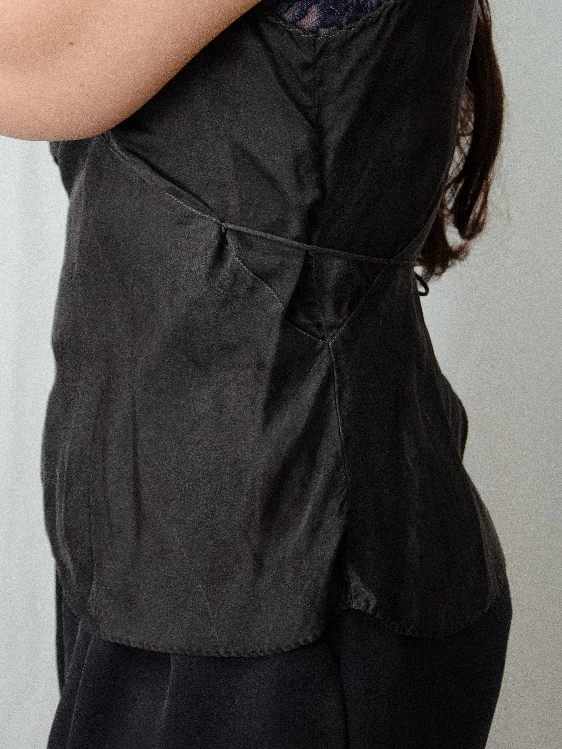Side detail of the 1930s black silk bias-cut top on a model, showing the tie cinching the waist.