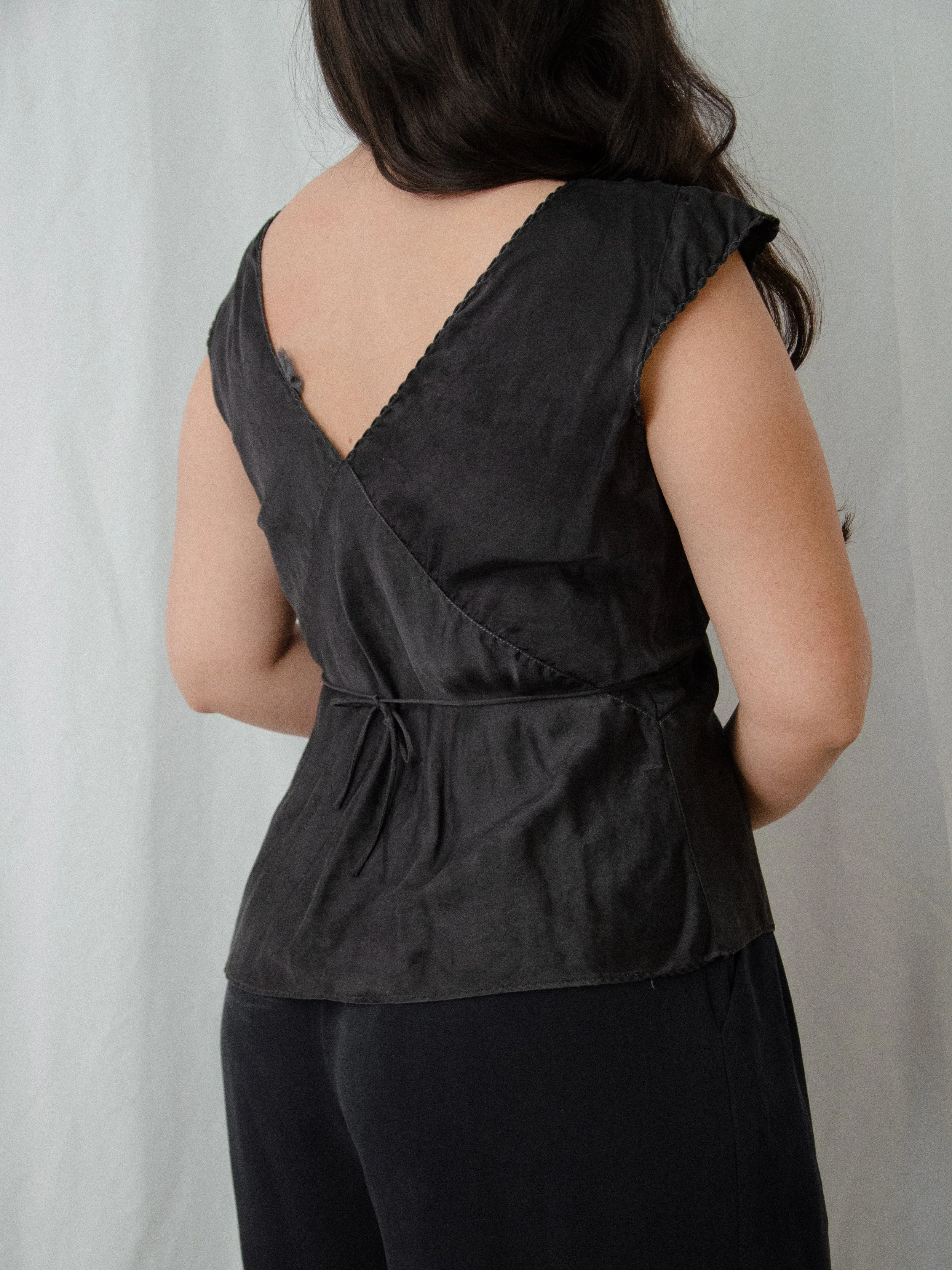 Back view of the 1930s black silk top on a model, showing the V-back and waist tie.