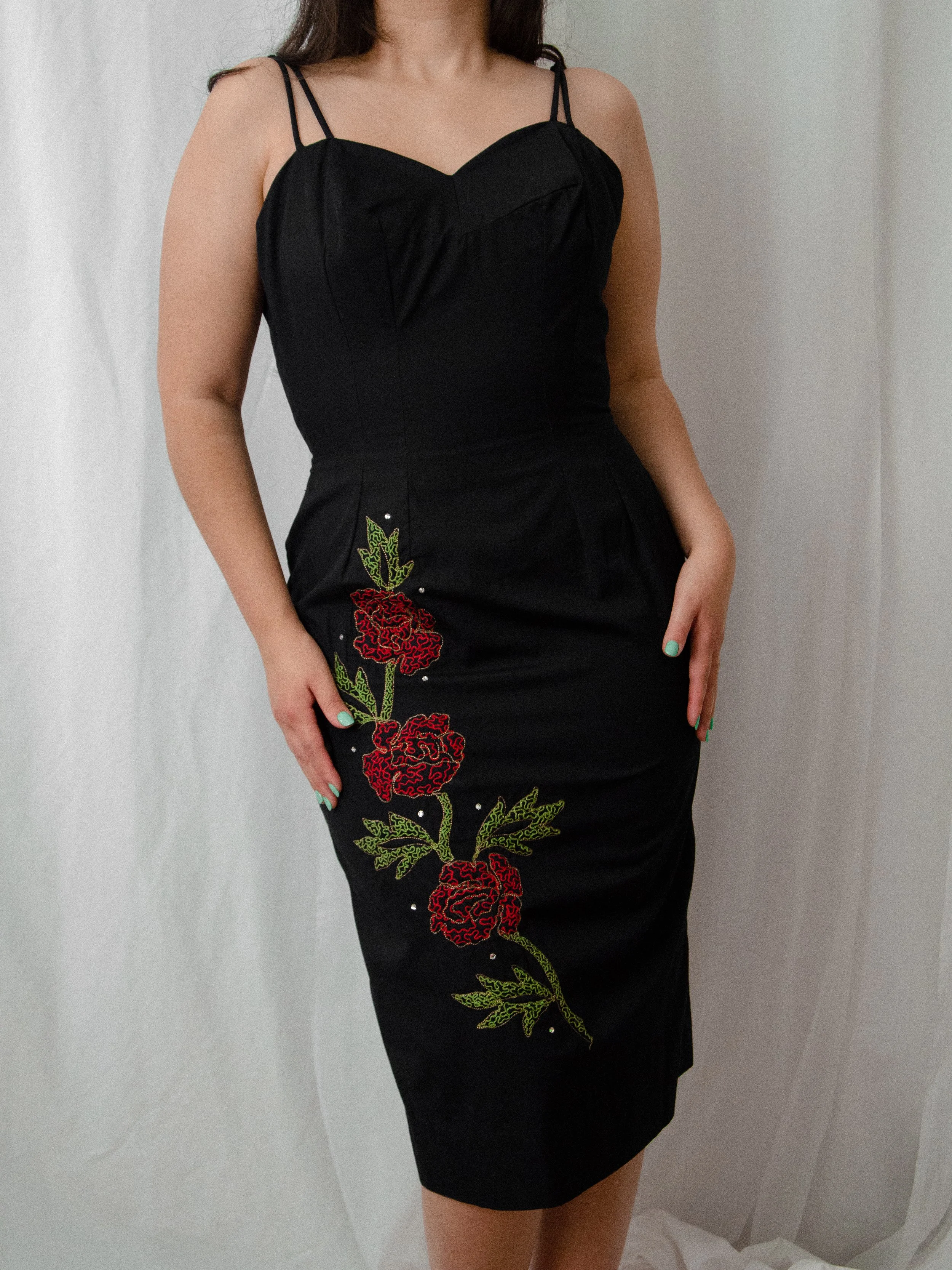 Front view of the 1950s black rosette wiggle dress on a model, showing the sweetheart neckline and double straps.