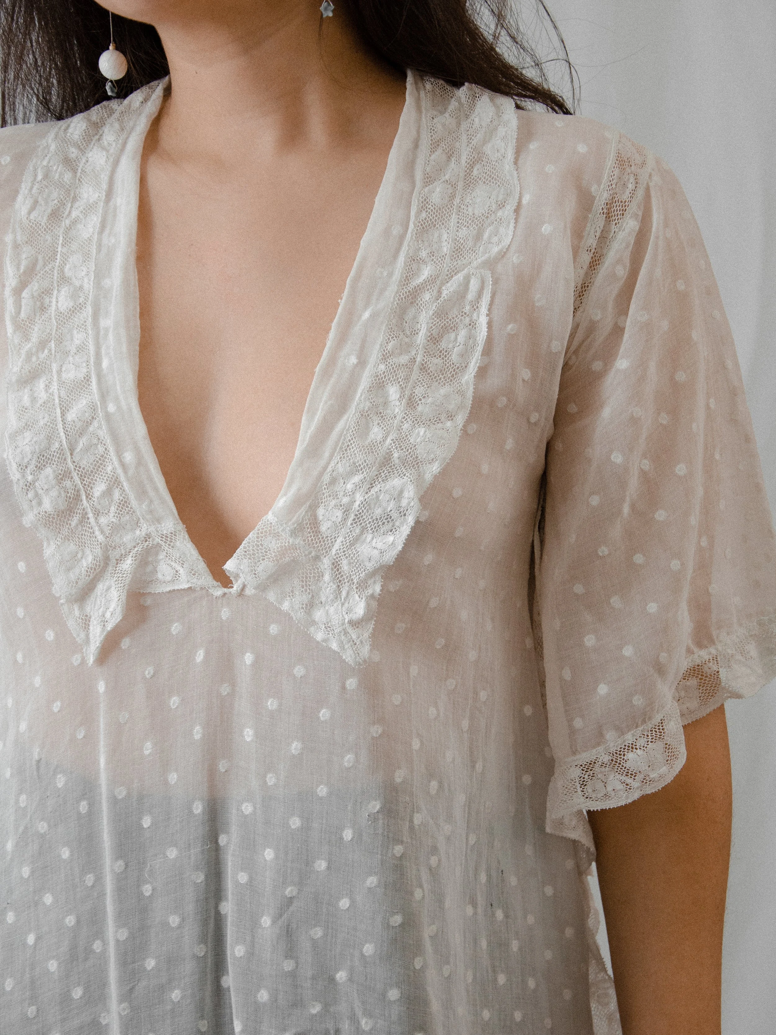 Close-up of the 1920s white cotton top's deep V lace collar and semi-sheer dotted fabric.