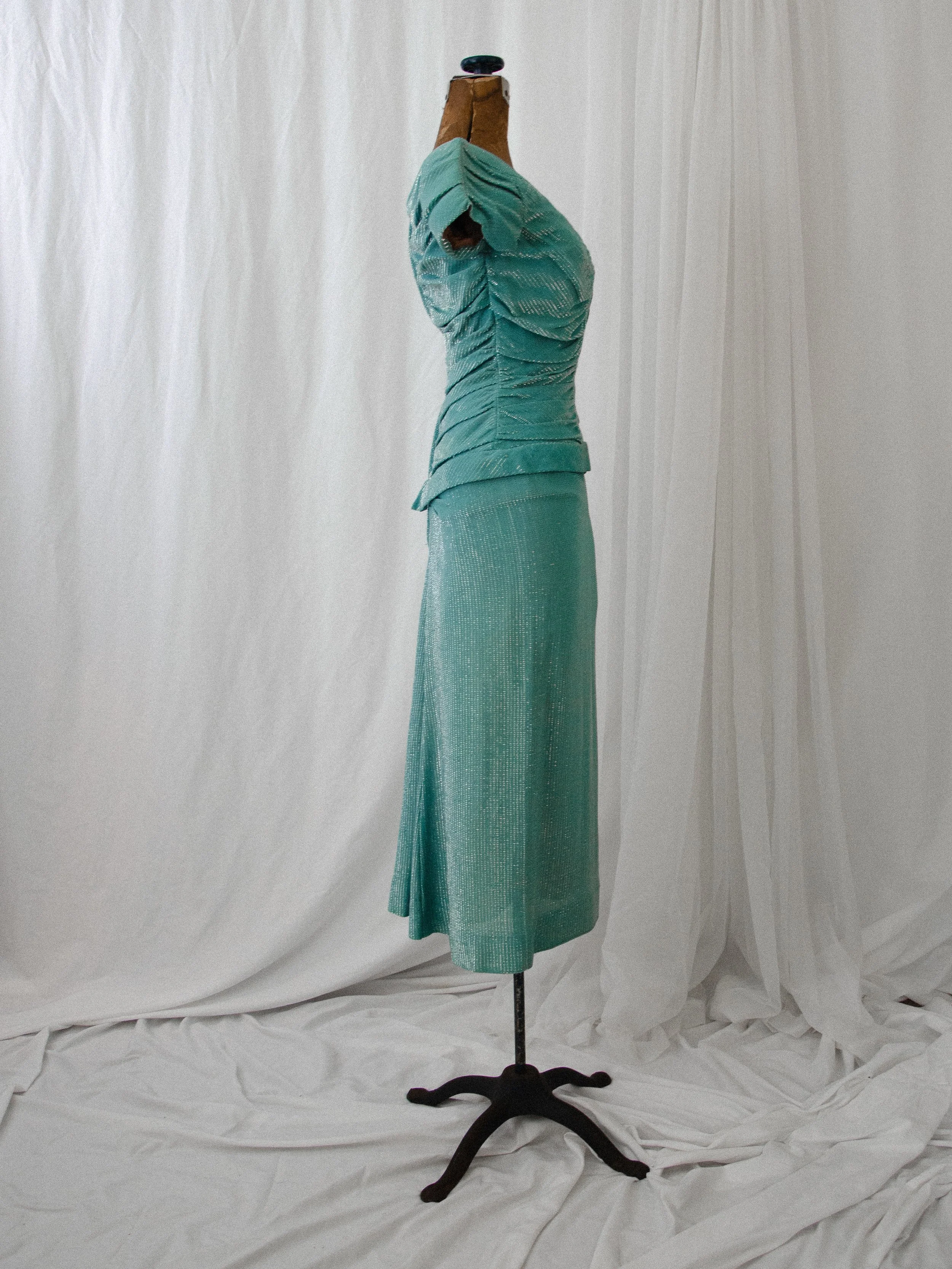 Opposite side view of the late 1940s turquoise and silver lamé dress on a dress form.