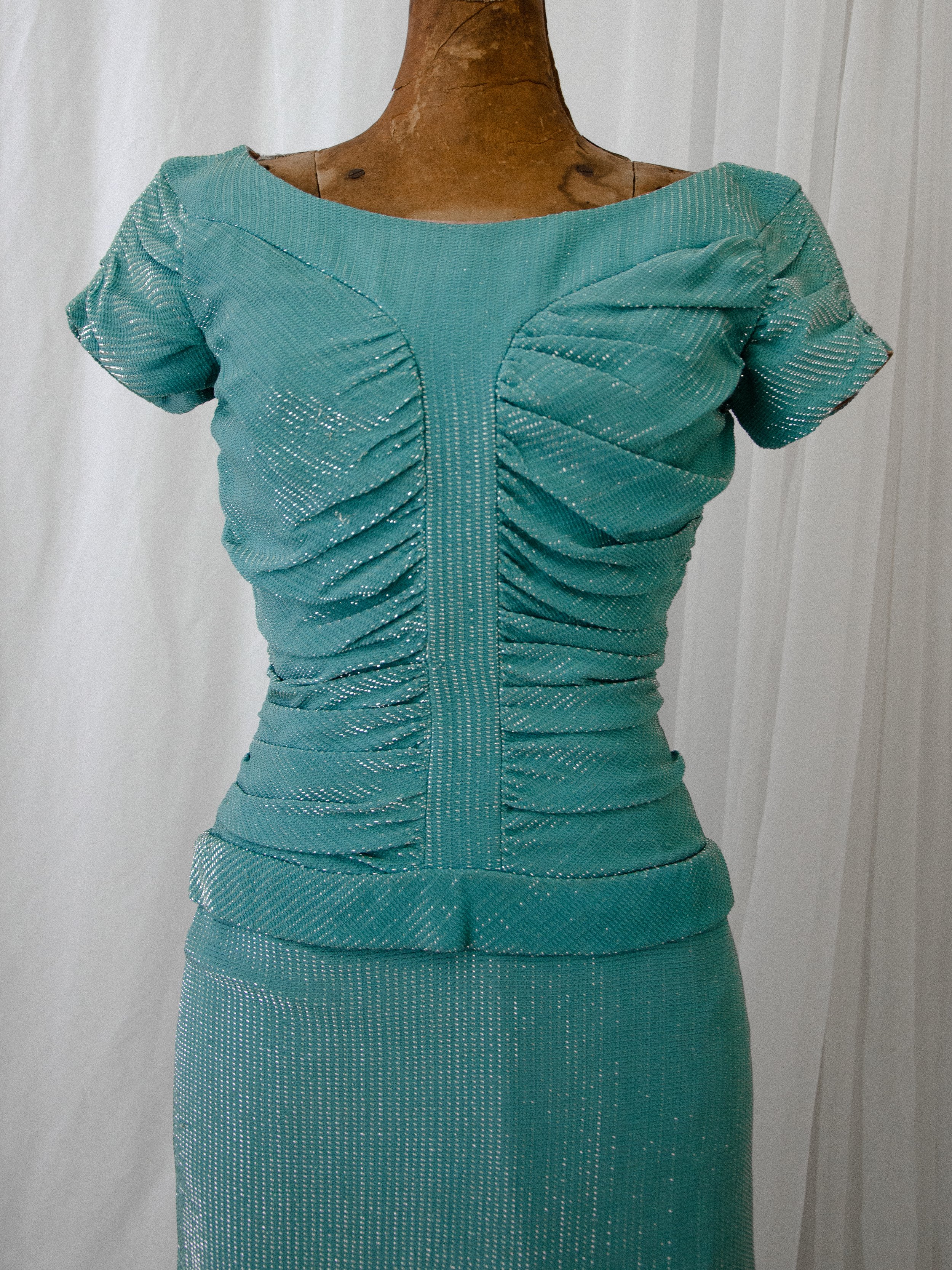 Close-up of the late 1940s turquoise lamé dress bodice, showing the ruched panels and short sleeves.