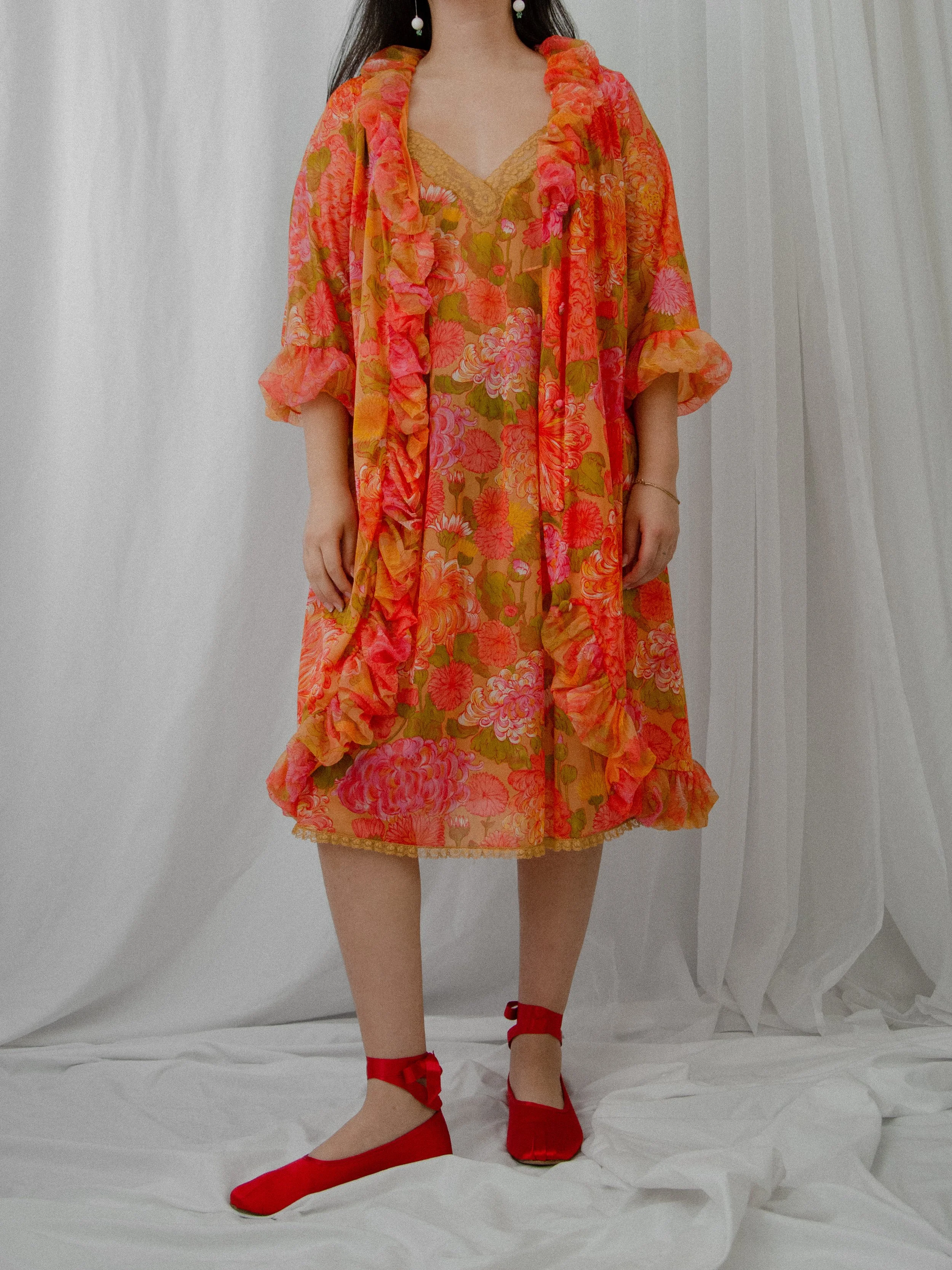 1960s orange floral peignoir robe worn open over the matching slip on a model, front view.