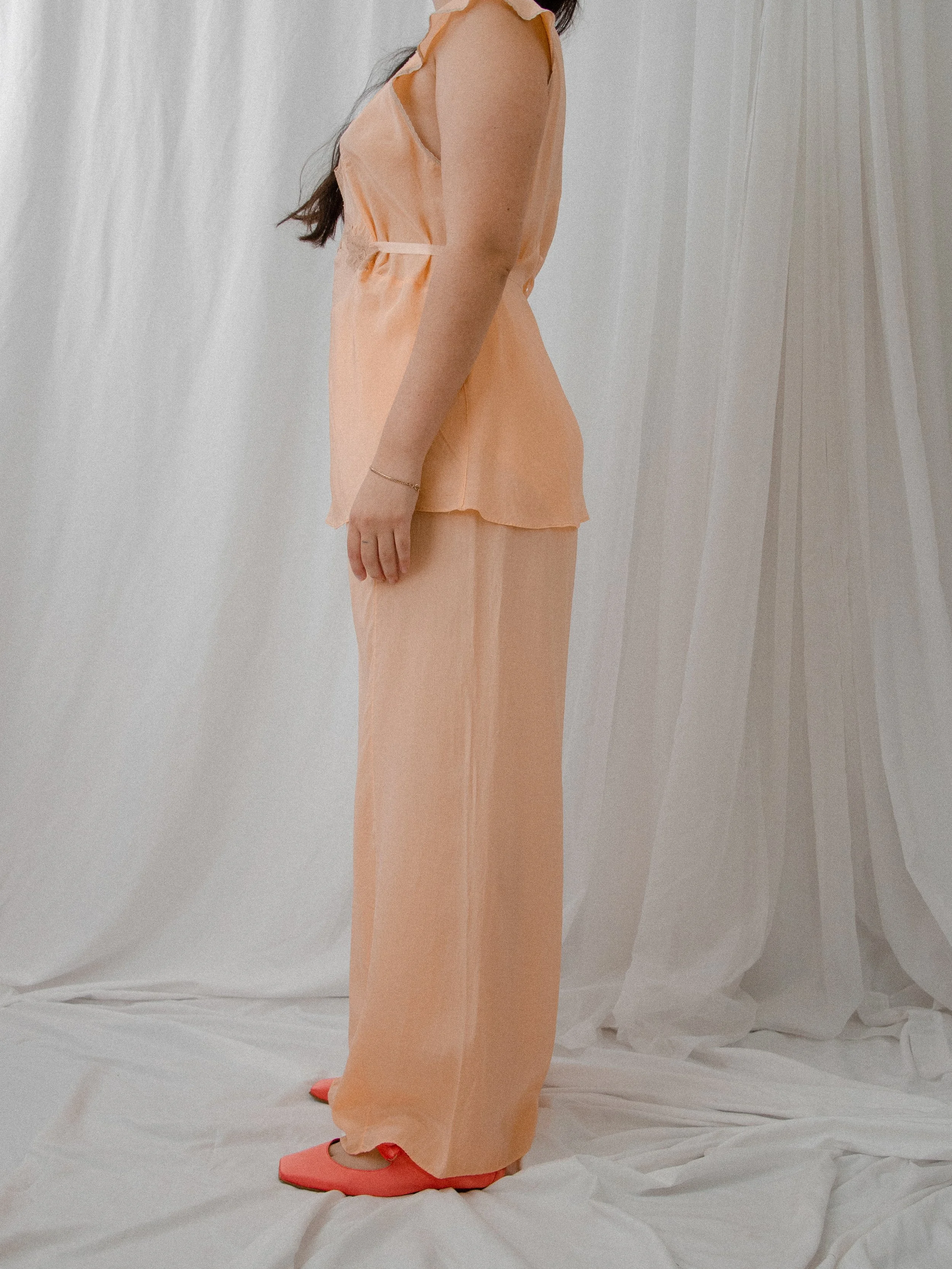Side view of the 1930s peach silk pajama set on a model, showing the waist tie and full-length pants.
