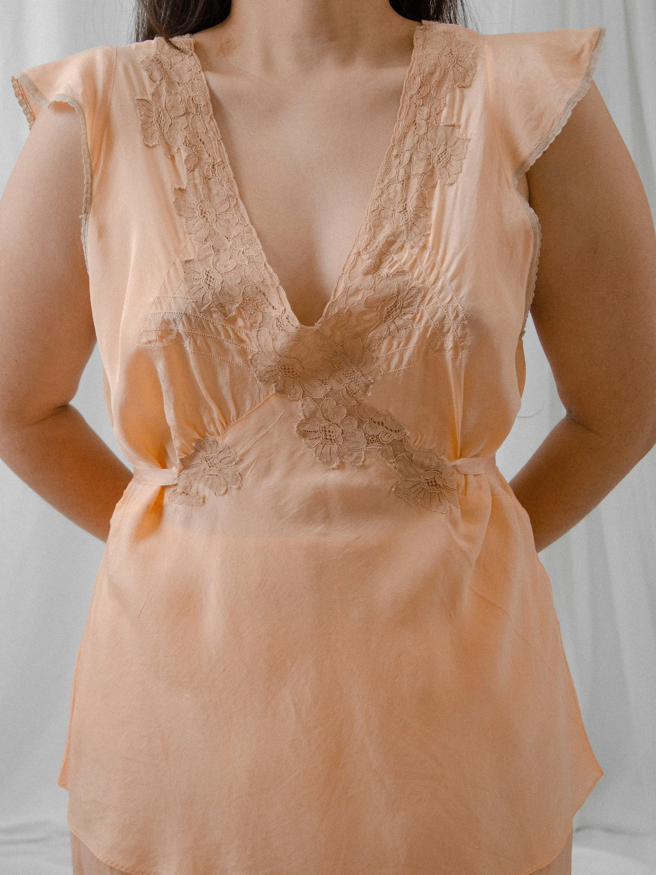 Close-up of the 1930s peach silk pajama top, showing the deep V neckline with tan lace and flutter sleeves.