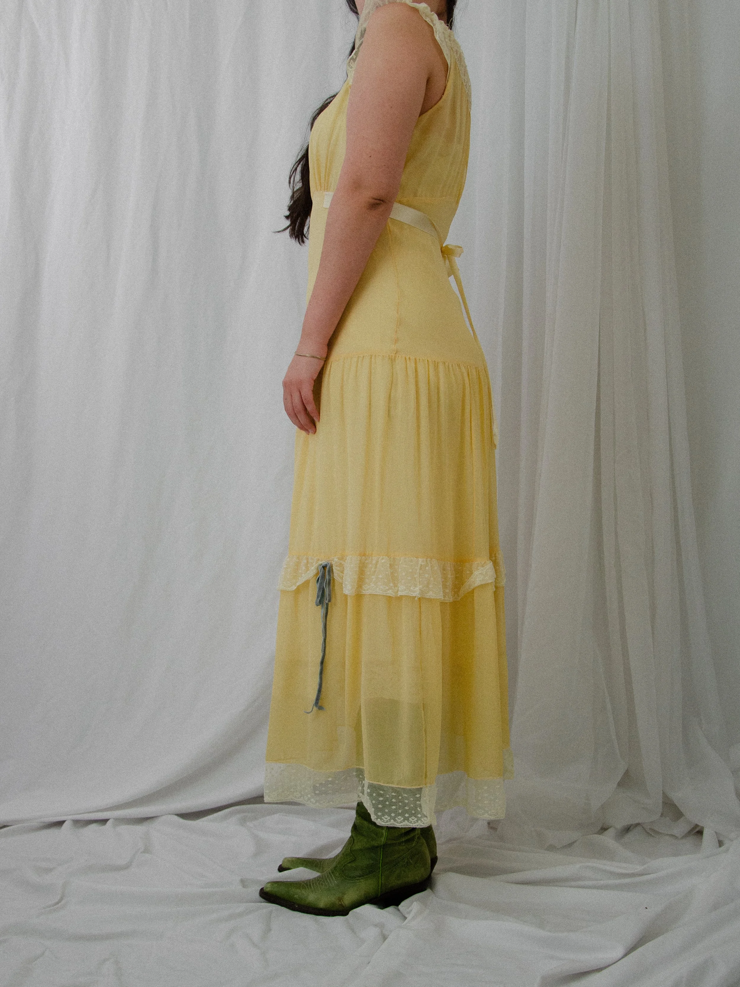 Side view of the 1940s canary yellow silk dress on a model, showing the tiered skirt and velvet bow.