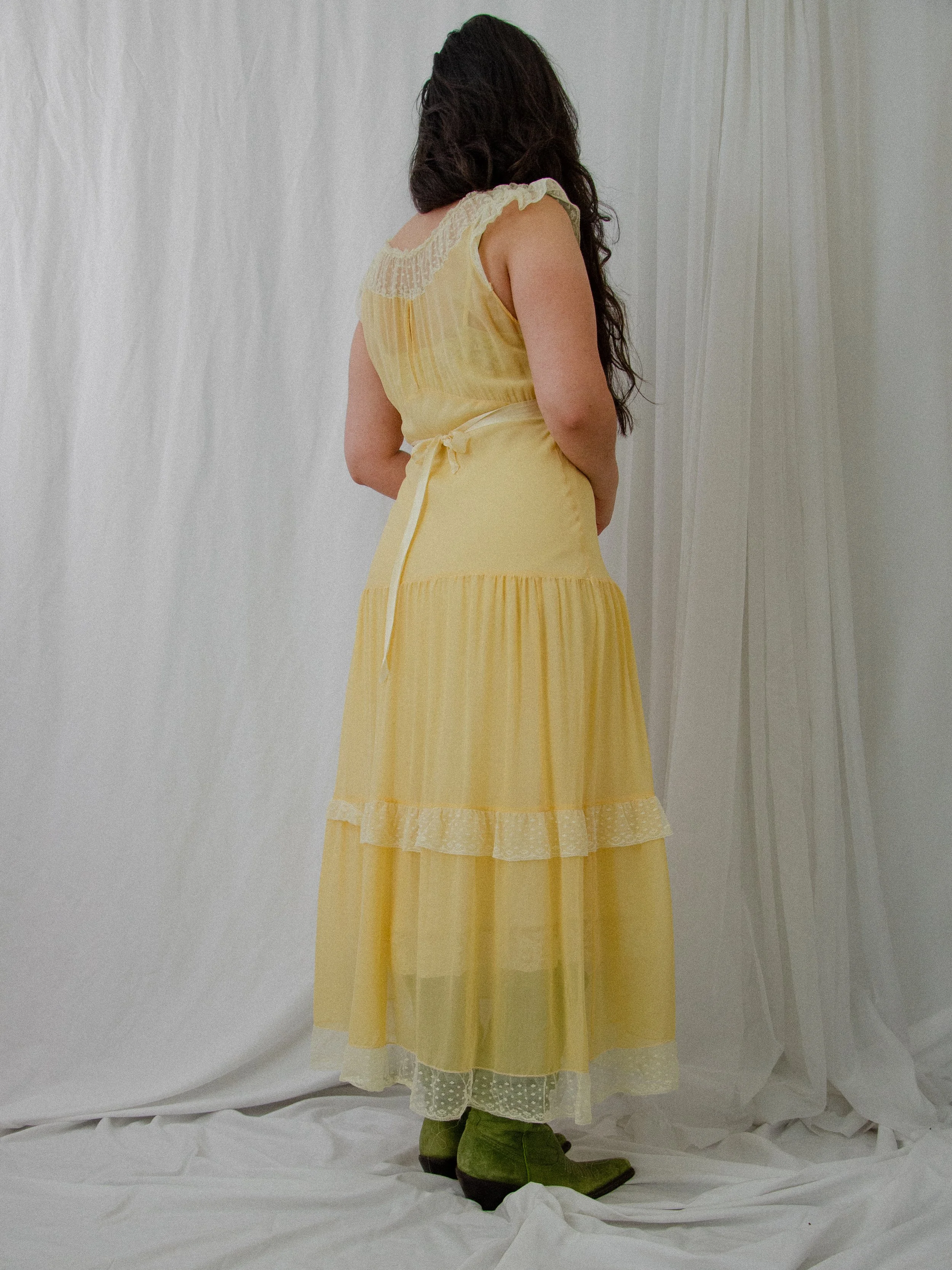Back view of the 1940s yellow silk dress on a model, showing the silk ribbon tie at the waist.