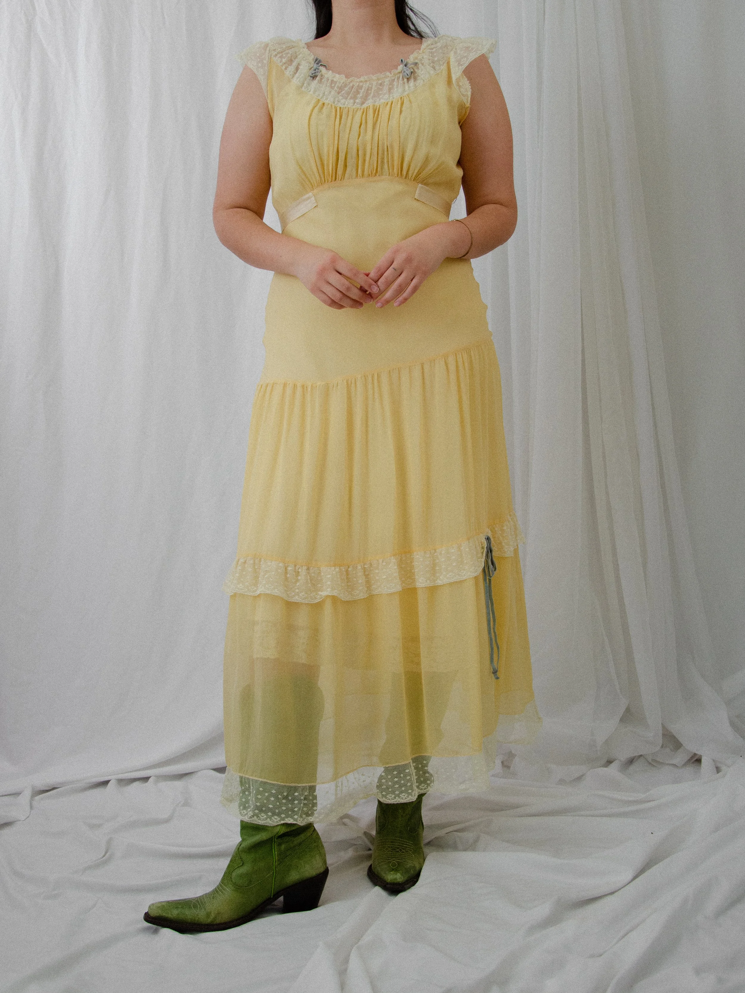 Front view of the 1940s sheer yellow silk dress on a model, showing the empire waist and lace-trimmed tiers.