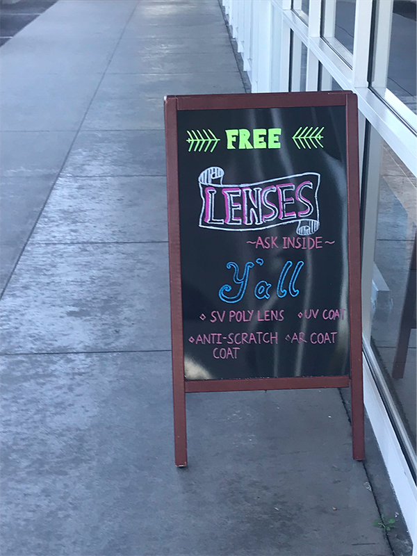 Chalk sign outside a store that reads: Free Lenses. Ask inside y'all.