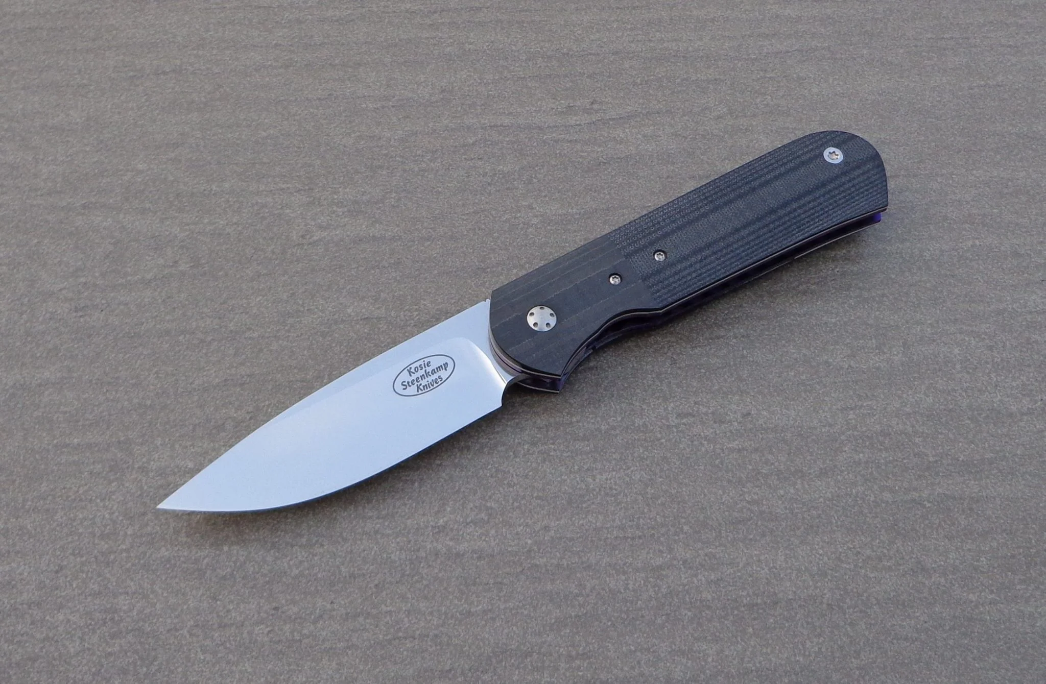 Knife: Samson Liner Lock. Blade: Böhler N690 Stainless Steel. Liners: Titanium, anodized blue. Handle scales: Carbon Fiber and G10 with anodized Titanium belt clip.
