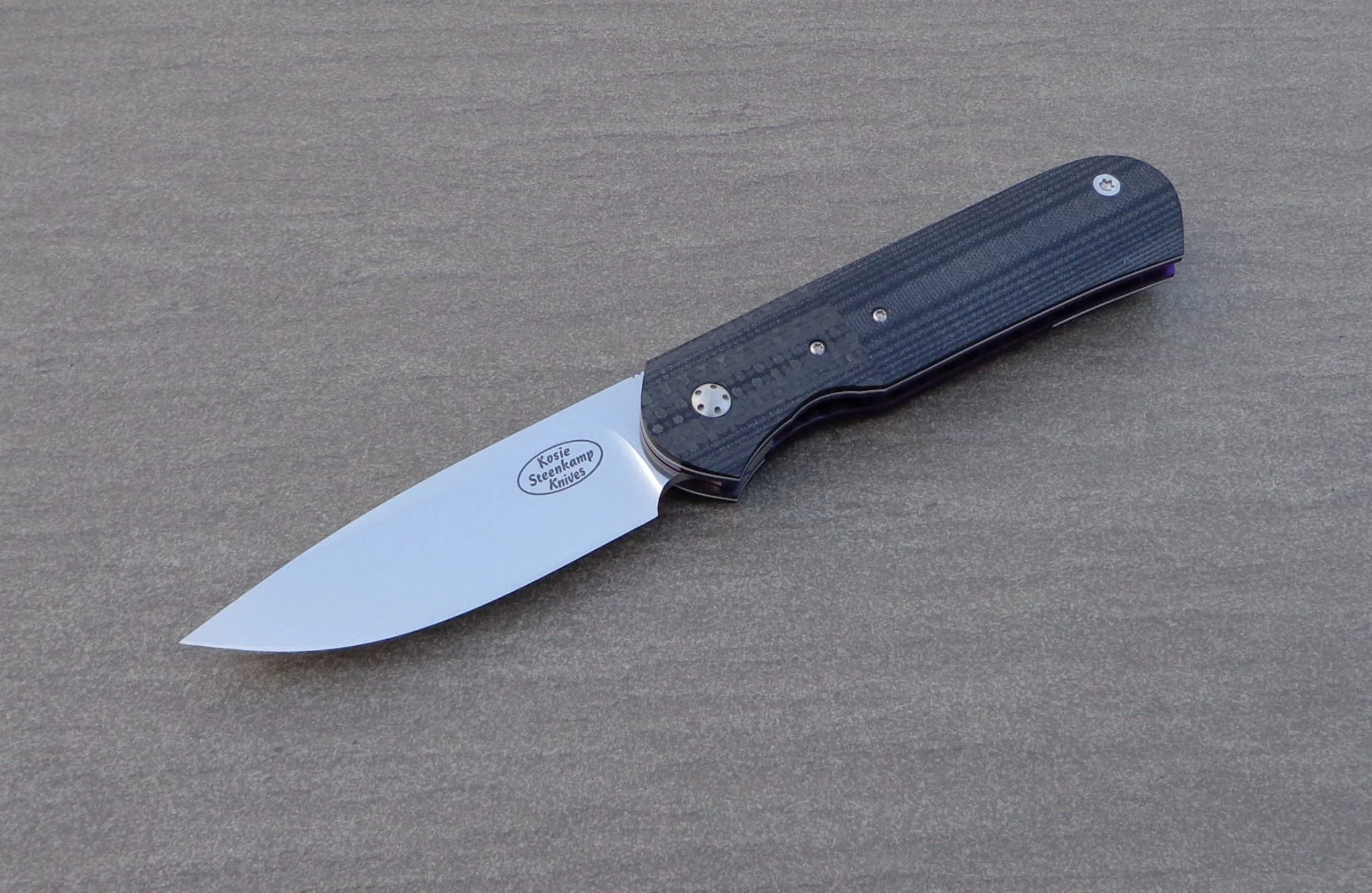 Knife: Samson Liner Lock. Blade: Böhler N690 Stainless Steel. Liners: Titanium, anodized blue. Handle scales: Carbon Fiber and G10 with anodized Titanium belt clip.