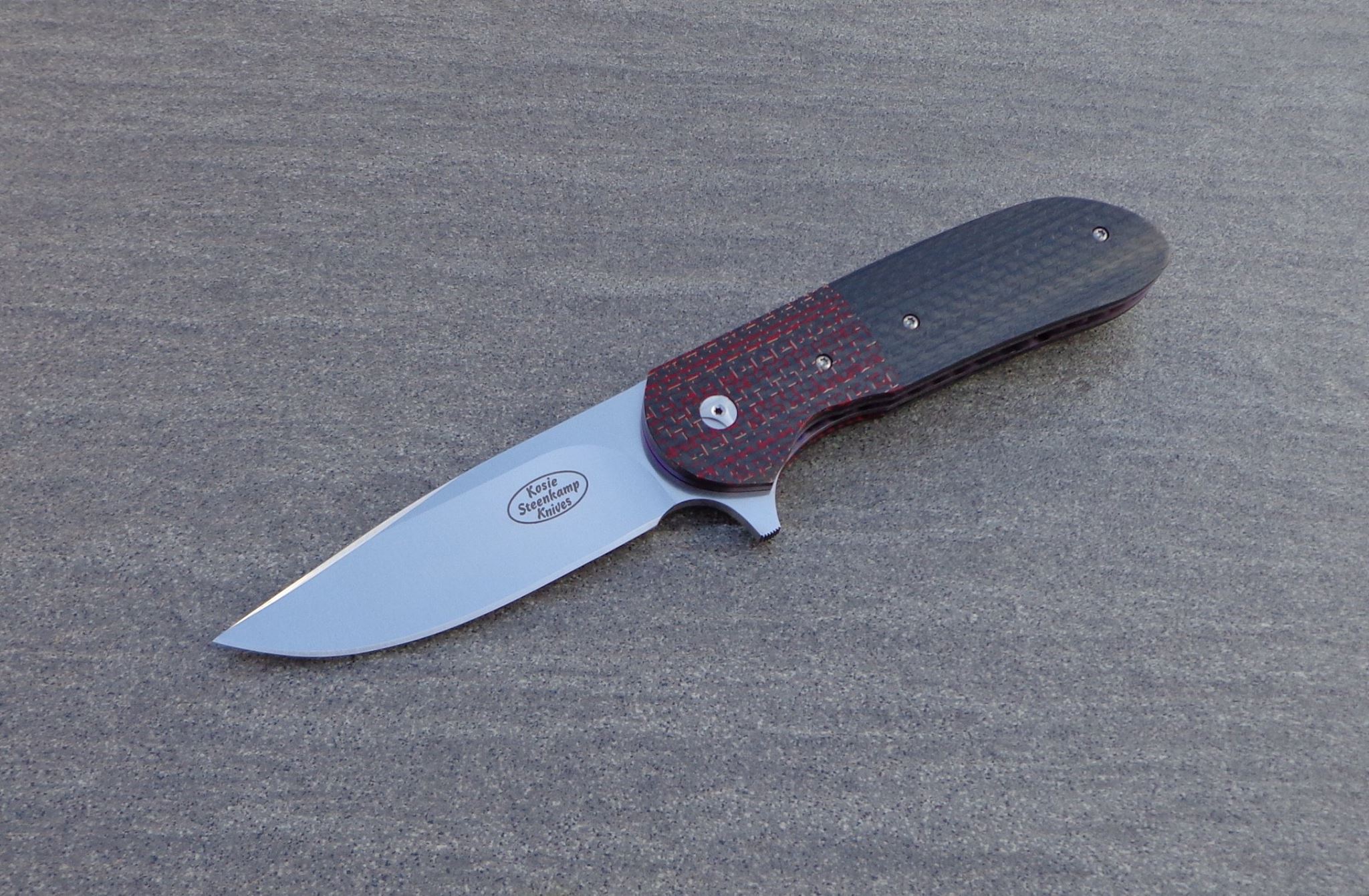 Knife: Piuma Flipper Liner Lock. Blade: Böhler N690 Stainless Steel. Liners: Titanium, anodized blue. Handle scales: Carbon Fiber with anodized Titanium belt clip. Bearing system.