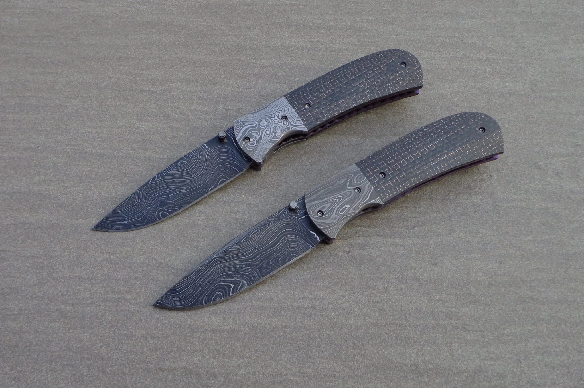Knifes: Sakson II Liner Locks. Blades: Alabama Damascus Steel. Bolsters: Alabama Damascus Steel. Liners: Titanium, anodized blue. Handle scales: LS Carbon Fiber with anodized Titanium belt clip.