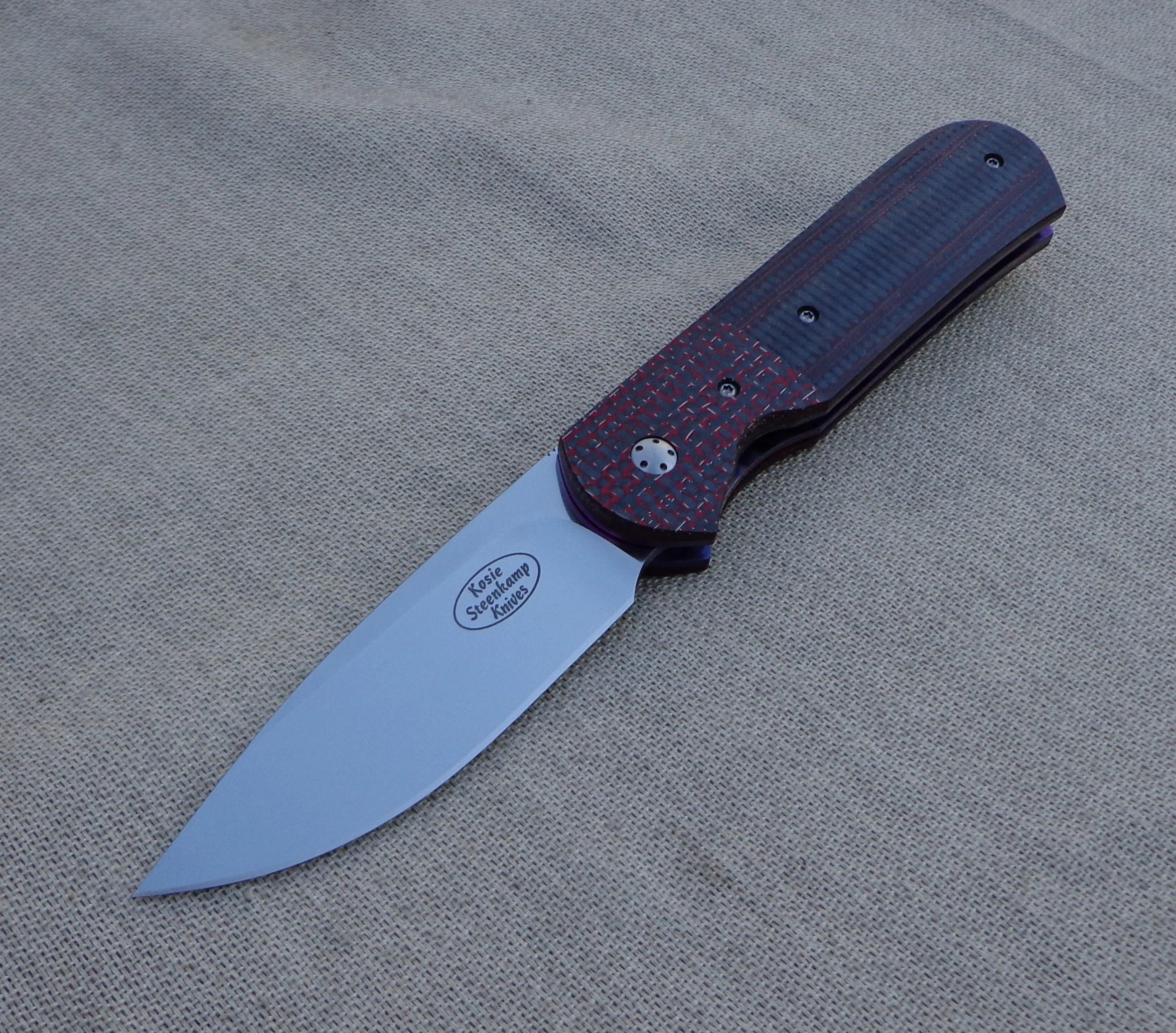 Knife: Samson Liner Lock. Böhler N690 Stainless Steel Blade. Titanium liners. Red LSCF and Carbon Fiber + G10 handle. Titanium belt clip.