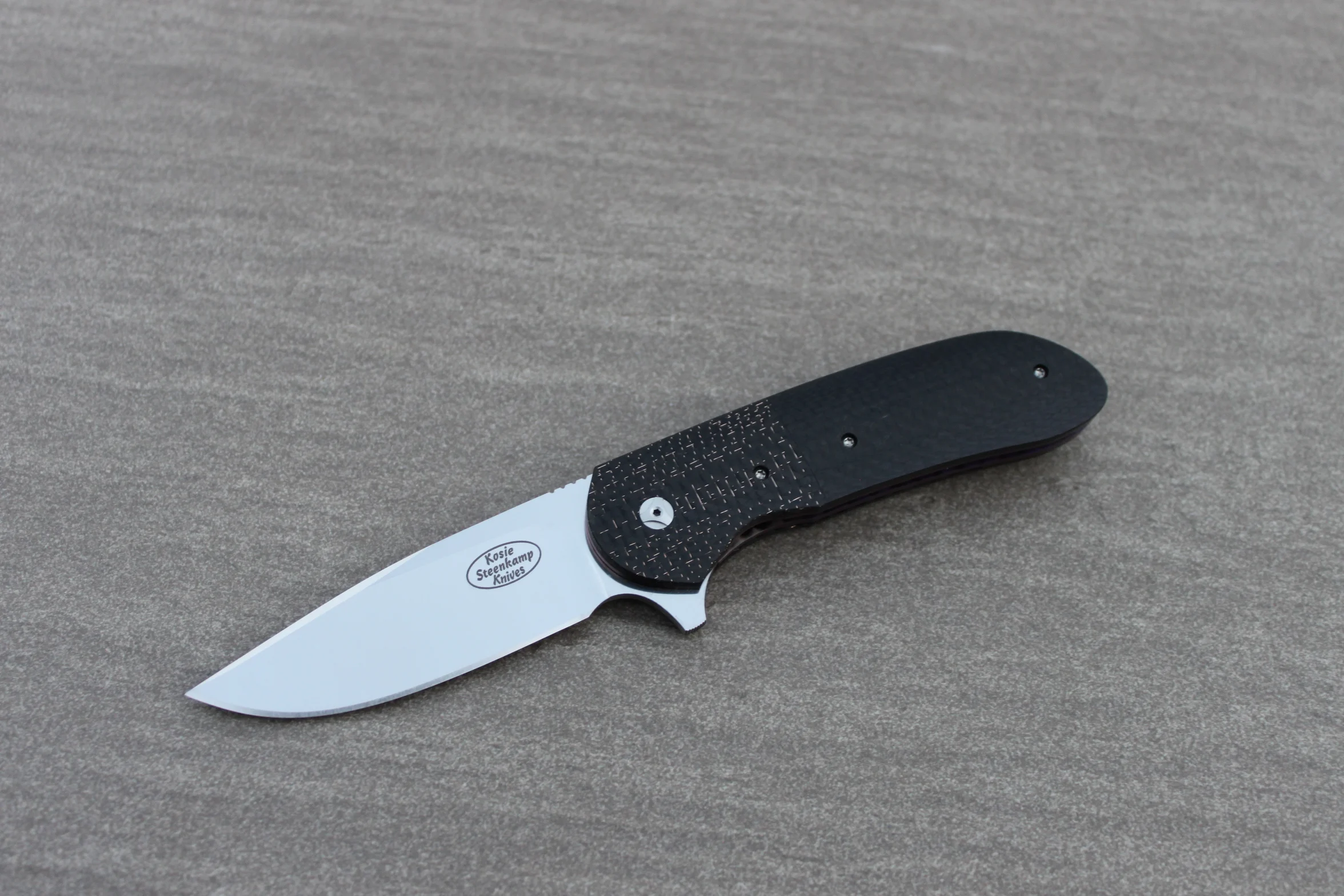 Knife: Piuma Flipper Liner Lock - IKBS. Böhler N690 Stainless Steel blade. Titanium liners with bronze LSCF + black CF handle scales. Titanium belt clip.