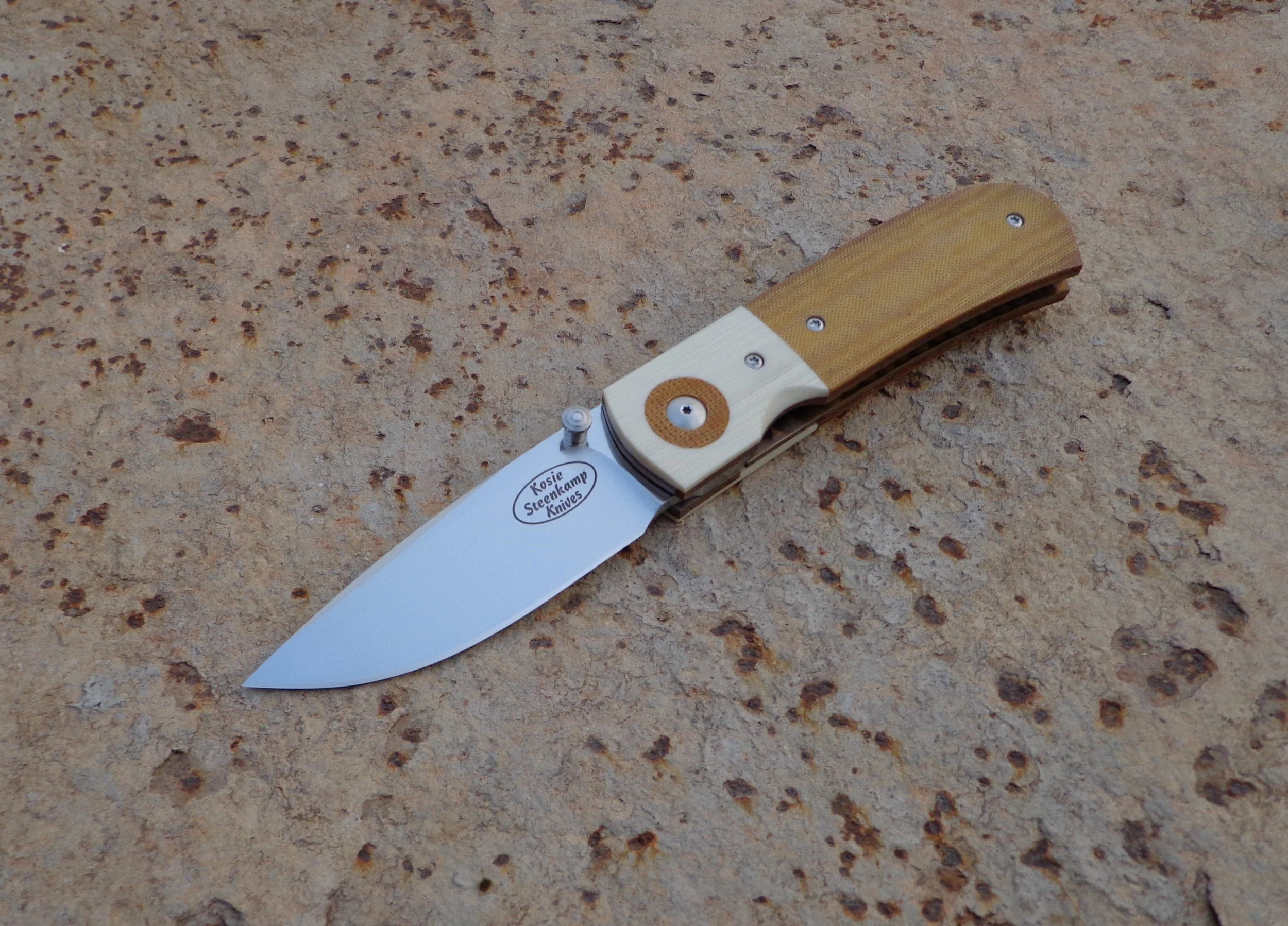 Knife: Sakson Junior Liner Lock. Blade: Böhler N690 Stainless Steel. Handle scales: G10 and Micarta. Liners and pocket clip: Titanium, anodized golden.
