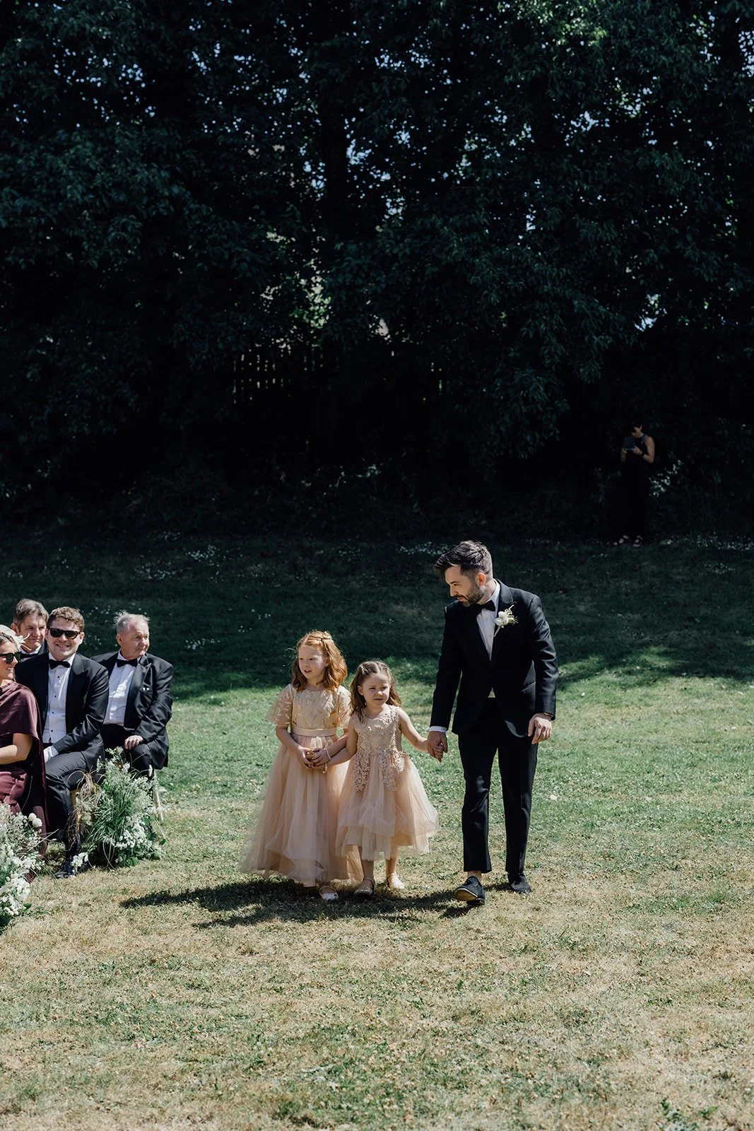 Flower girls walking down the aisle at an outdoor ceremony in East Cork Castlemartyr Resort