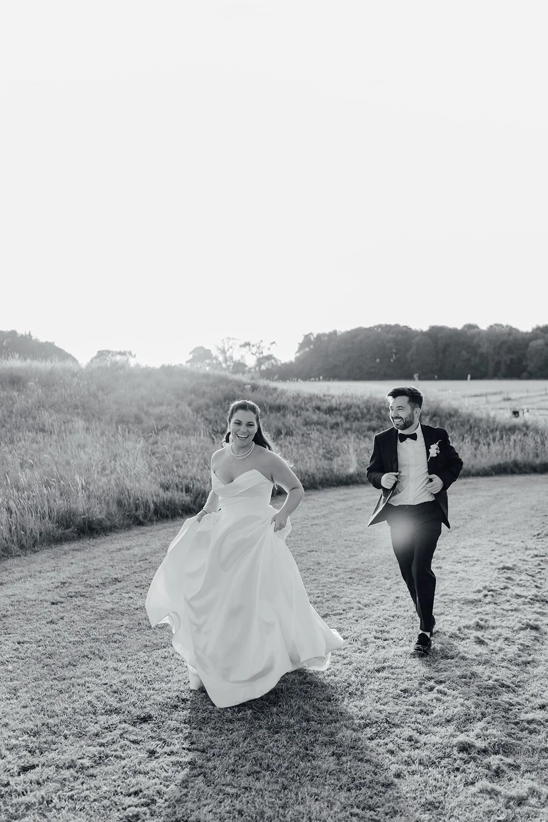 Black and white photo of the bride and groom running through the fields at Castlemartyr Resort