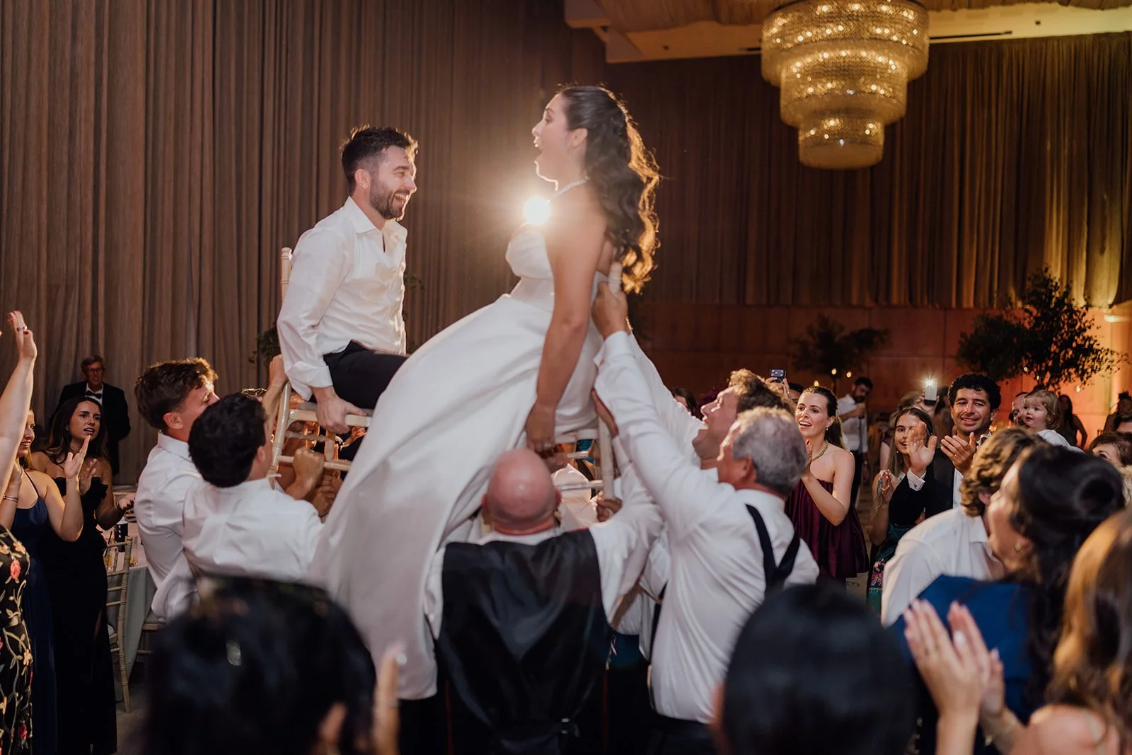 Bride and groom lifted on chairs during the hora at their wedding reception