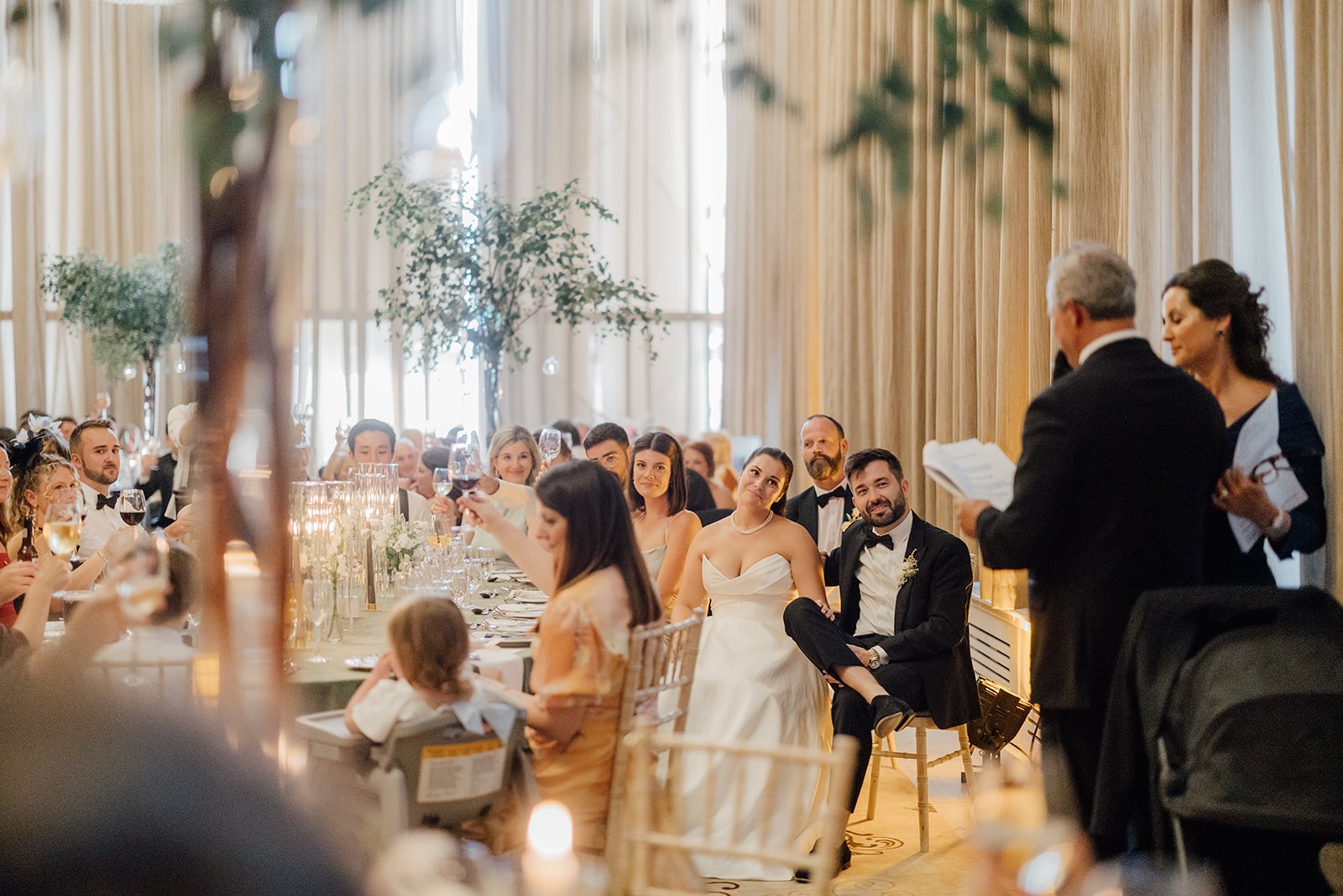 Bride and groom laughing with family and friends at a candlelit wedding dinner at Castlemartyr Resort