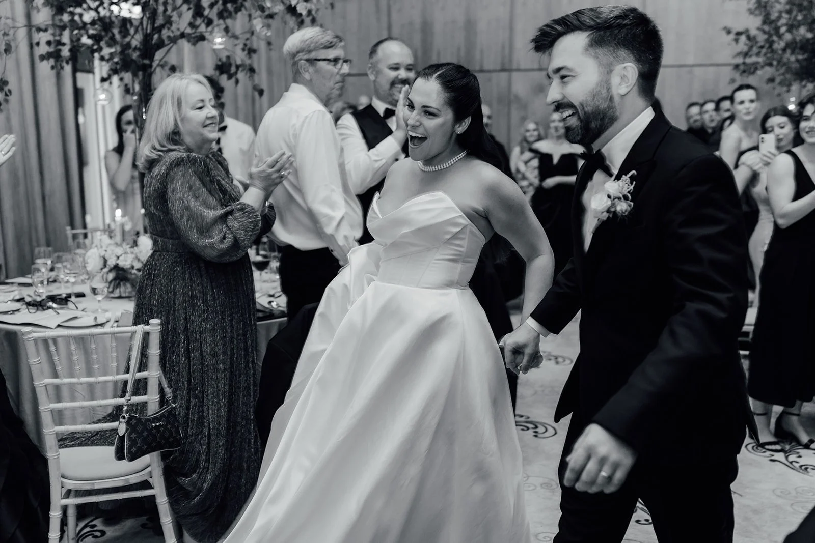 Black and white photo of the bride and groom celebrating with guests at their wedding reception
