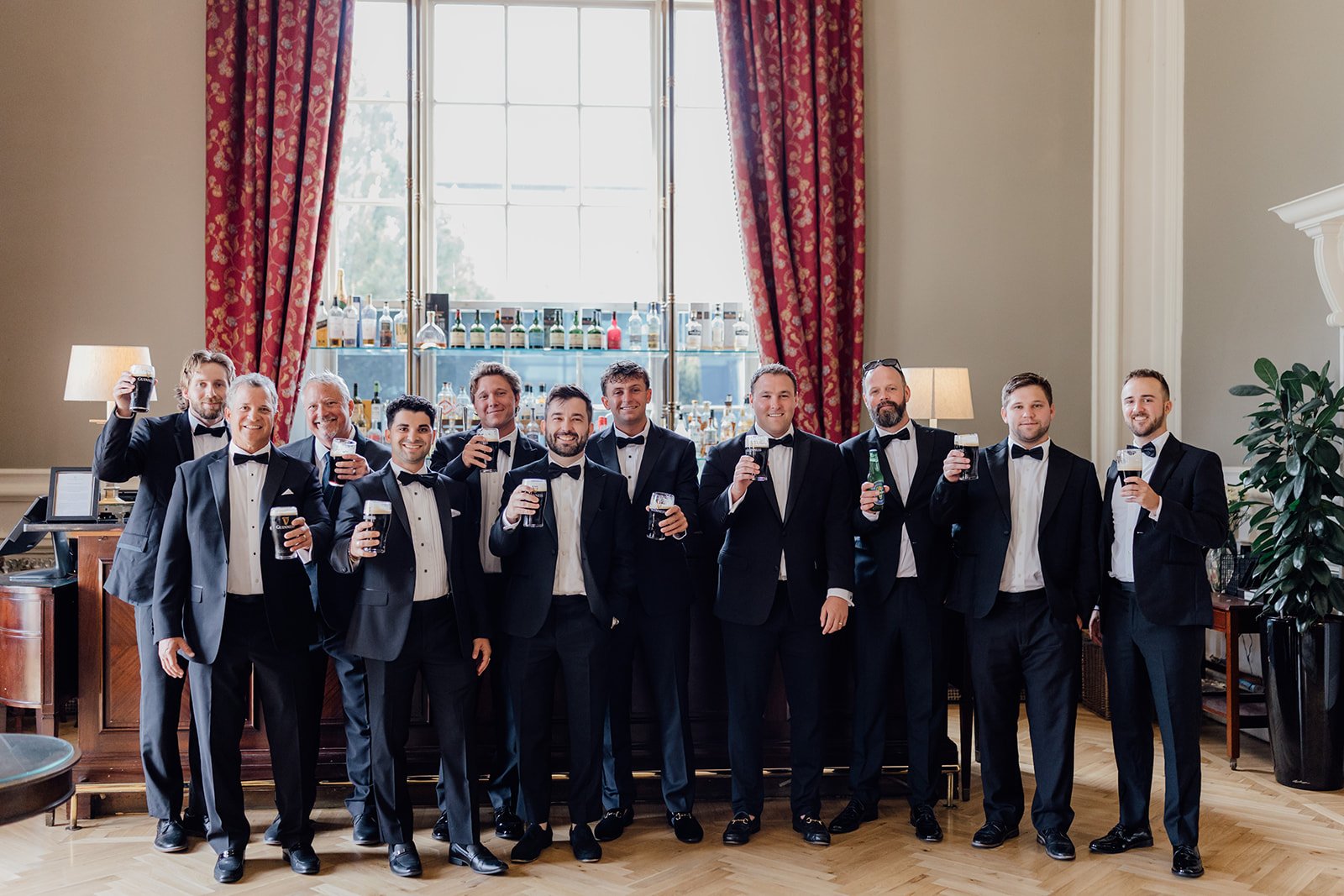 Groom and groomsmen raising pints of Guinness before the wedding ceremony in the Knights Bar at Castlemartyr Resort