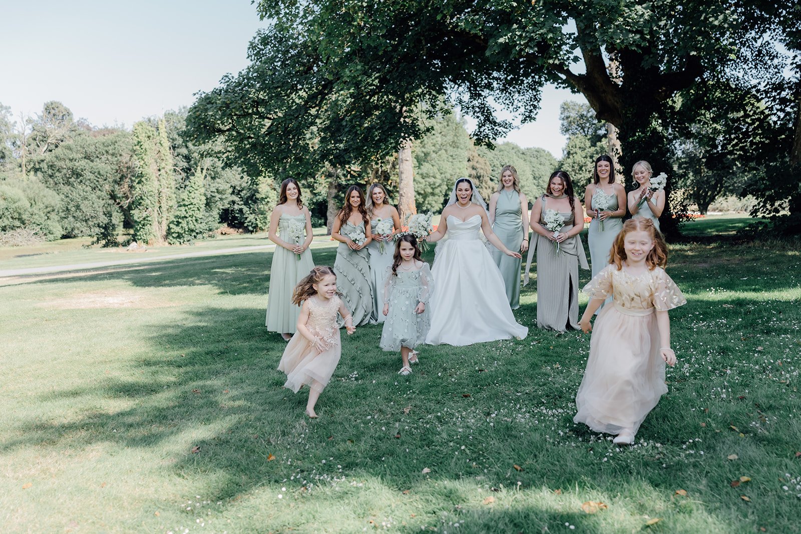 Bridesmaids and flower girls walking across the lawn at Castlemartyr Resort