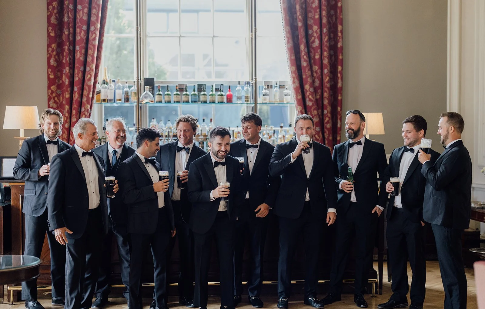 Groom and groomsmen raising pints of Guinness before the wedding ceremony in the Knights Bar at Castlemartyr Resort