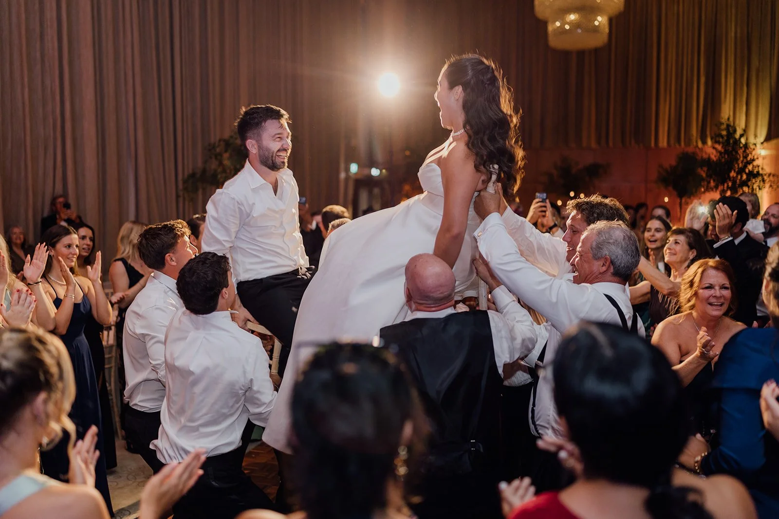 Bride raised up on a chair by guests during the hora at Castlemartyr Resort