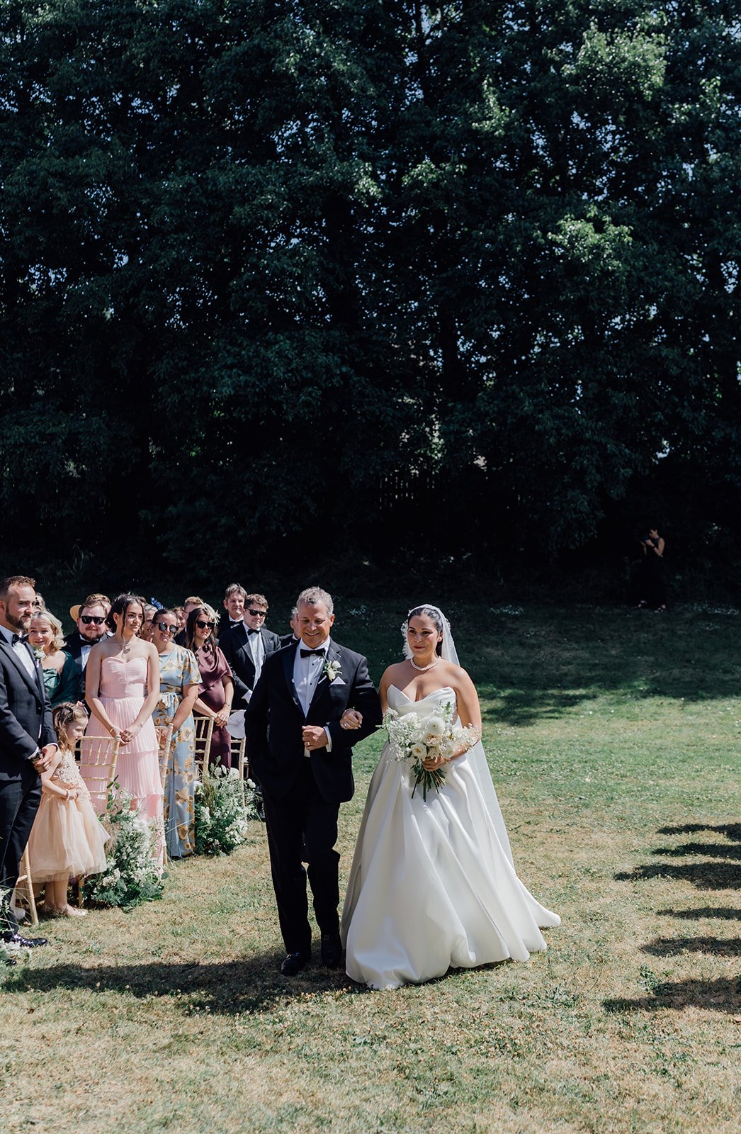 Bride walking down the aisle with her father as guests stand at Castlemartyr Resort