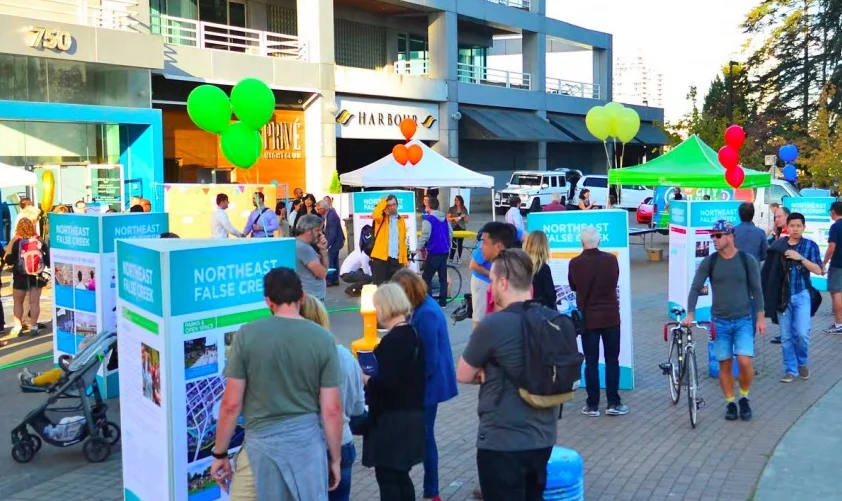 an image of PEOPLE LOOKING AT LARGE northeast false creek DISPLAY BOARDS AT AN OUTDOOR OPEN HOUSE at the plaza of nations IN VANCOUVER.