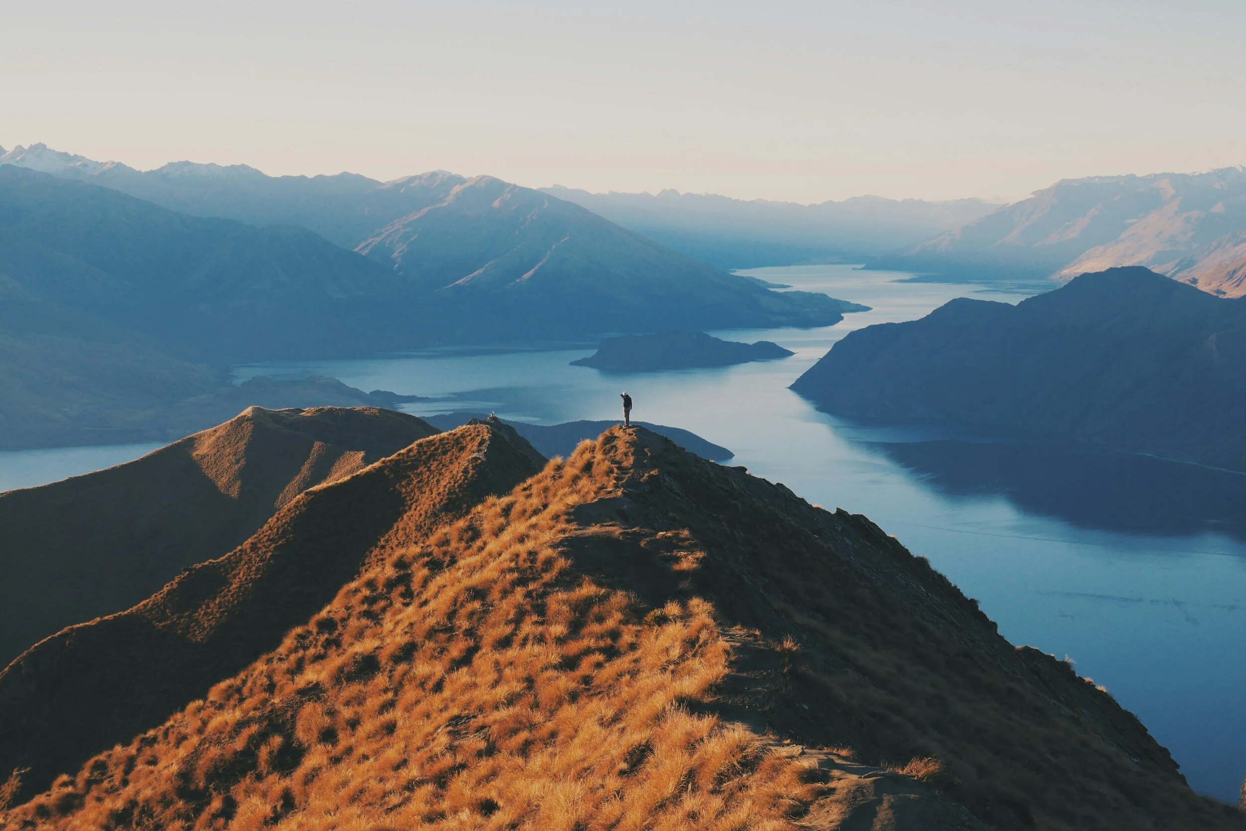 A hiker on top of a mountain overlooking a lake